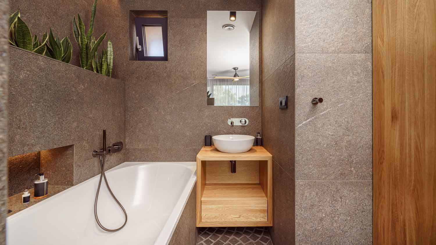 The interior of a small bathroom with plants over the bathtub