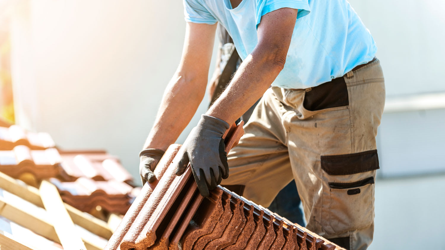 A tiler covering a roof with new tiles