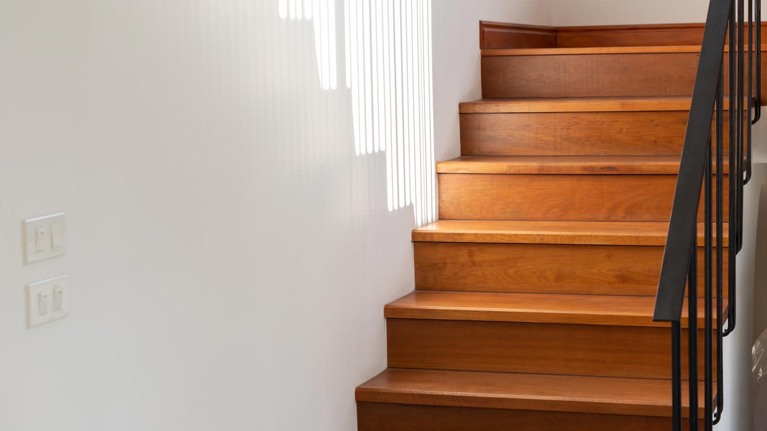 A black steel stair railing on a wooden staircase