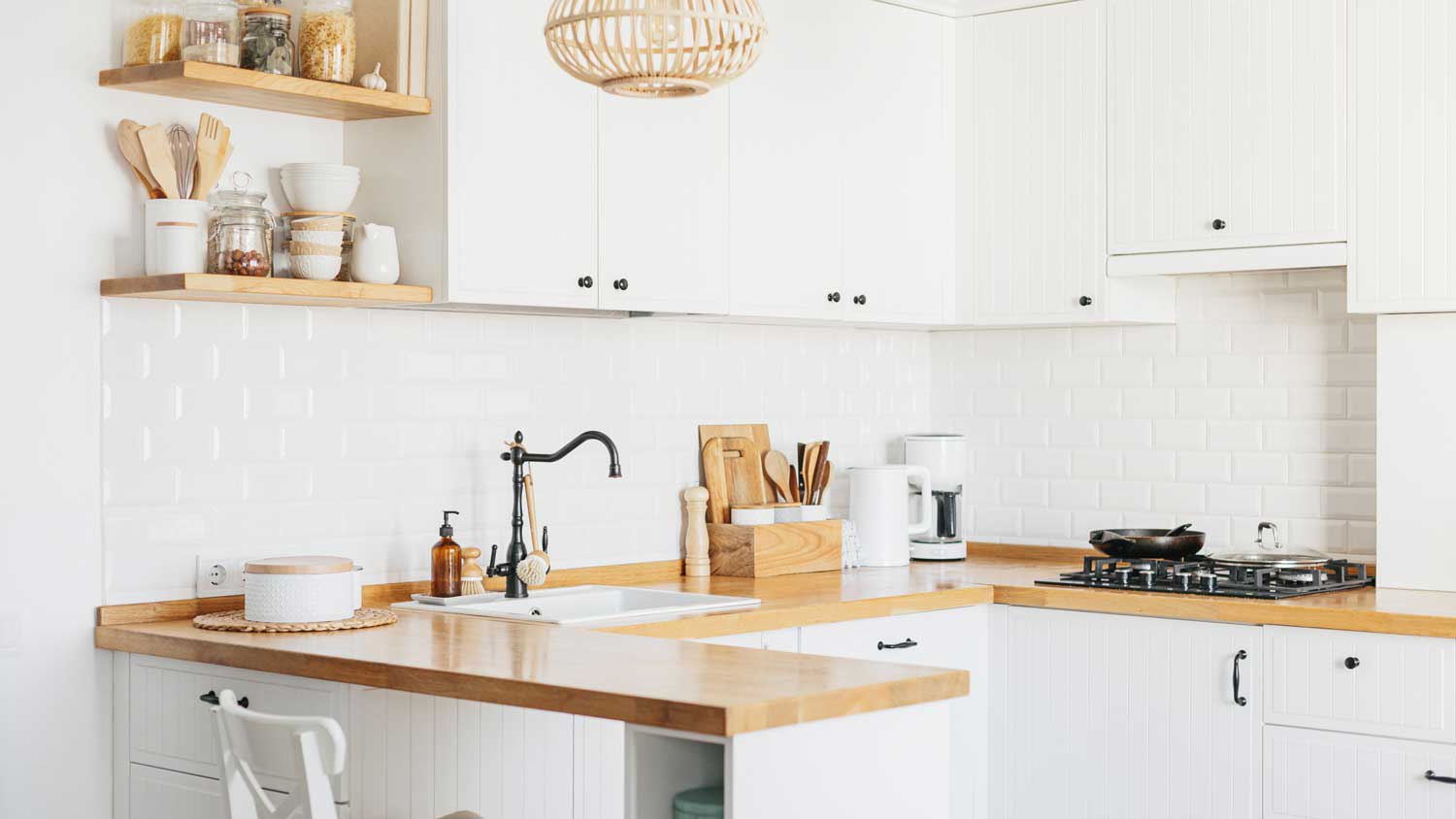 A bright small u-shape kitchen with white cabinets and wooden countertops