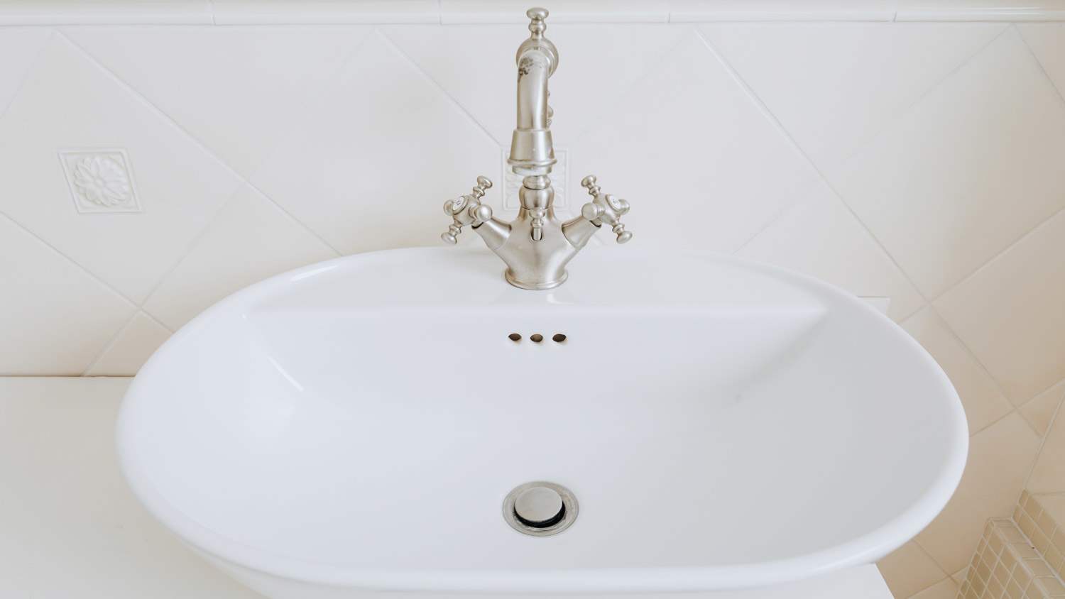 A porcelain bathroom sink with an old style tap