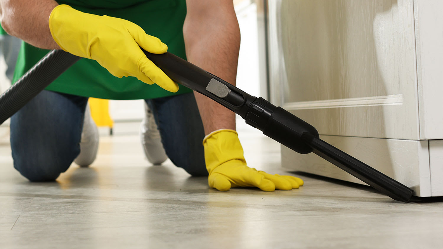 A closeup of a man vacuuming a pantry floor