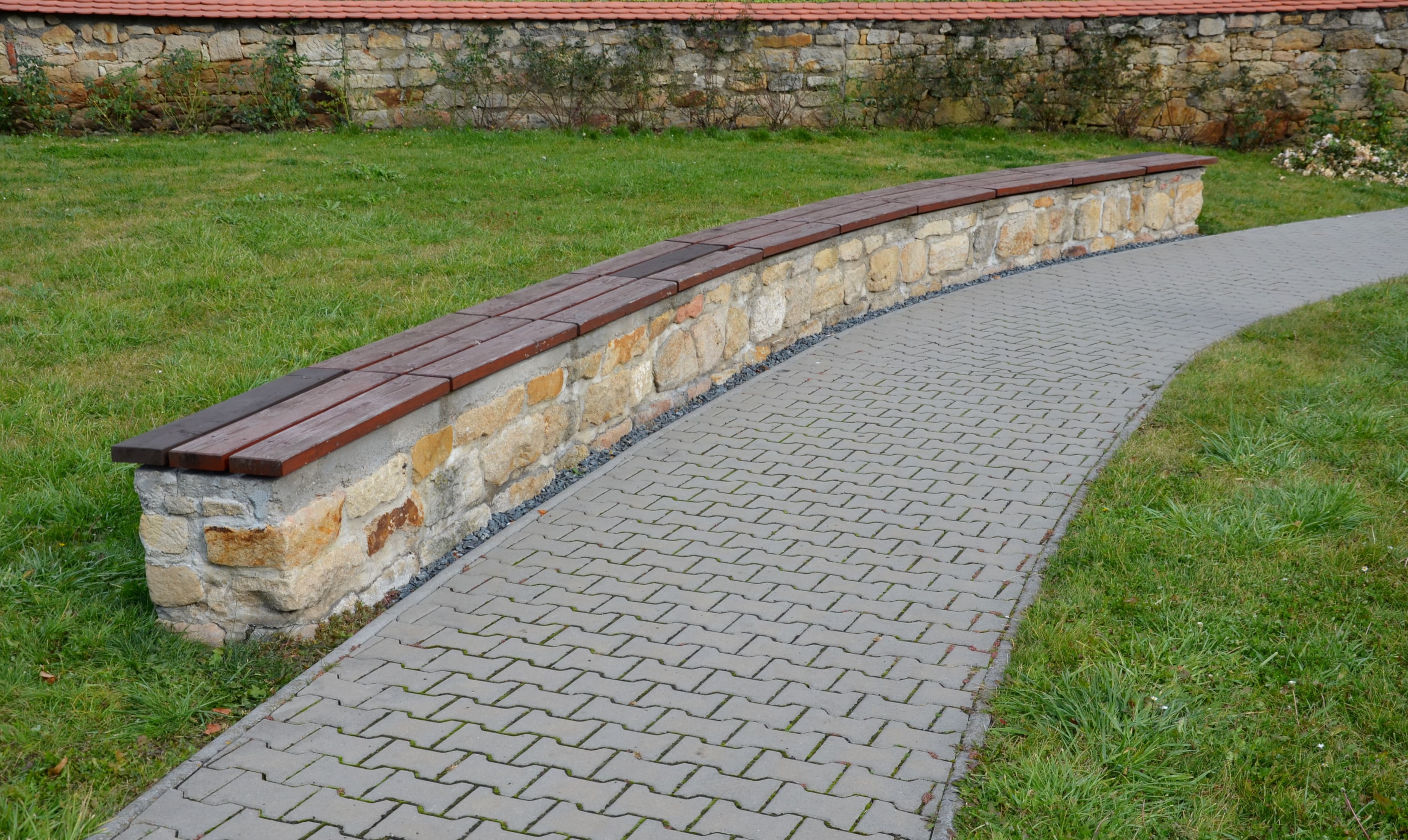 An open landscape featuring a short retaining wall with wood on top for sitting