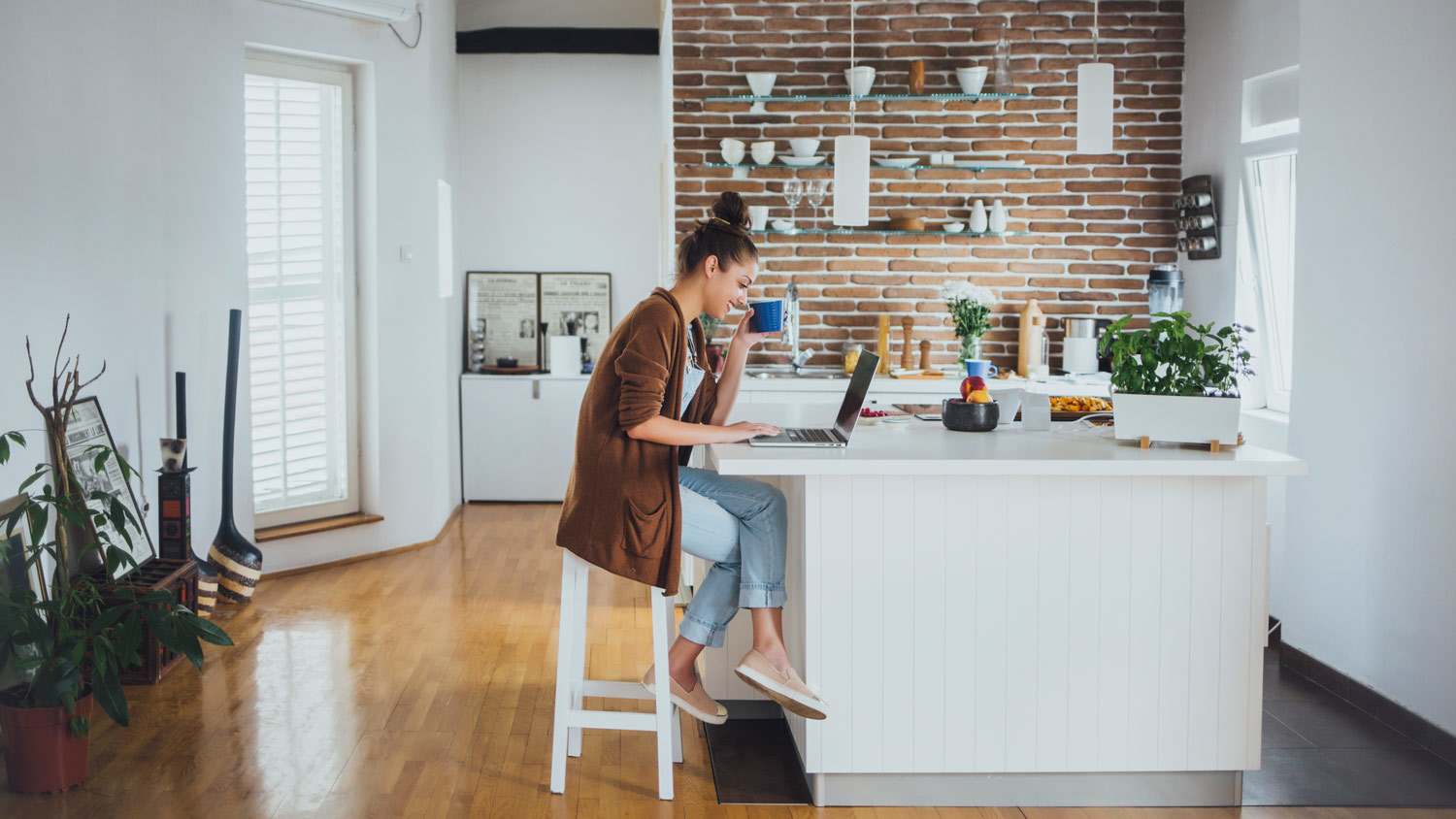 A young woman using her laptop on a kitchen island