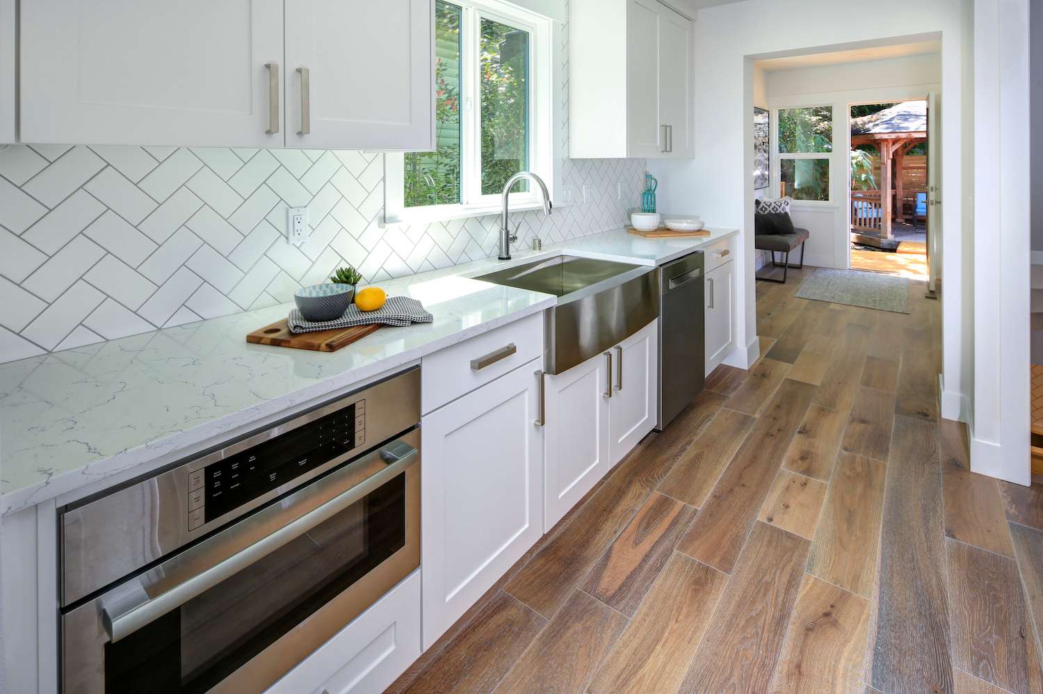 Kitchen with white herringbone backsplash and white cabinets