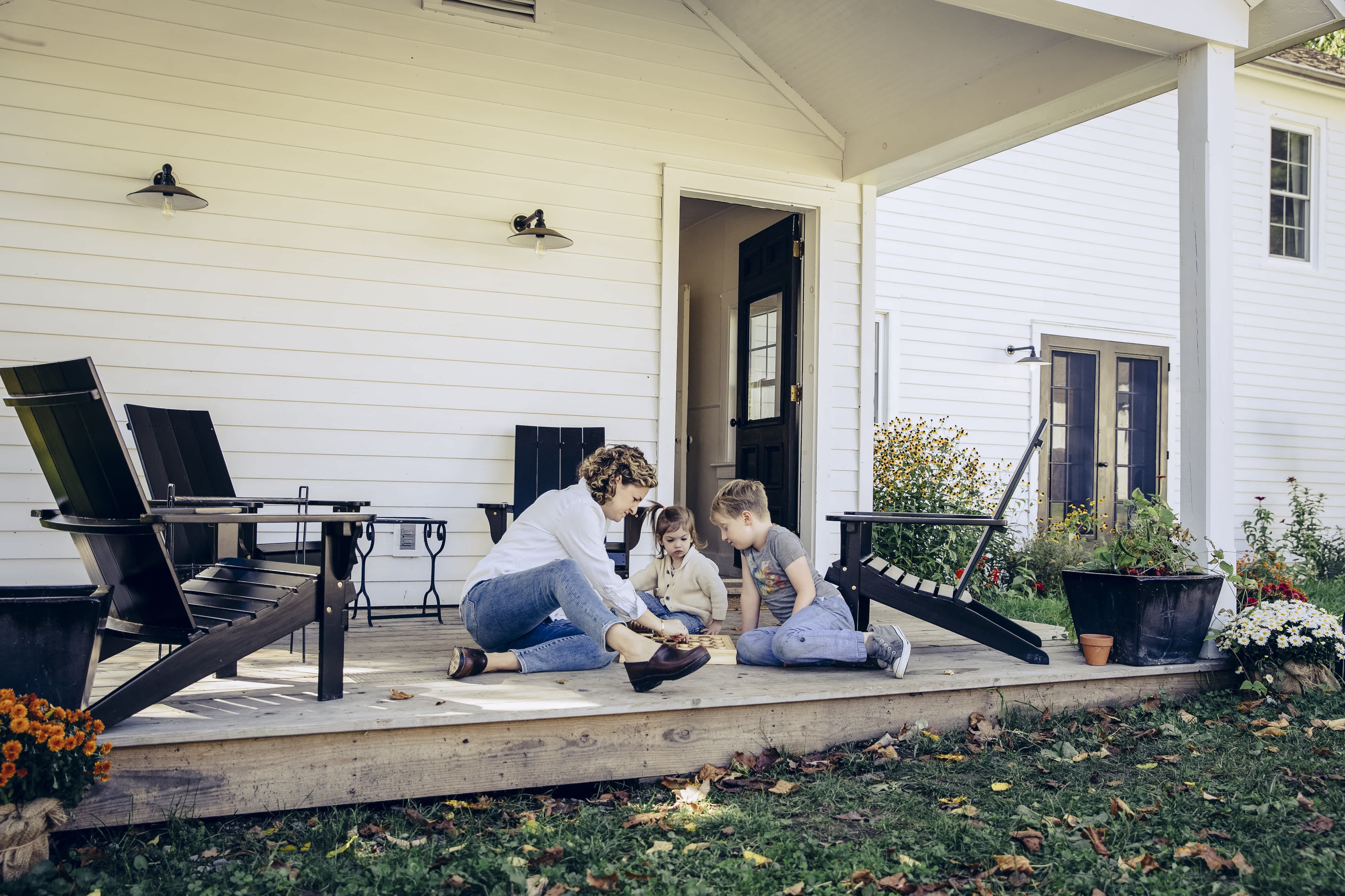 Mother and children playing checkers on outdoor porch