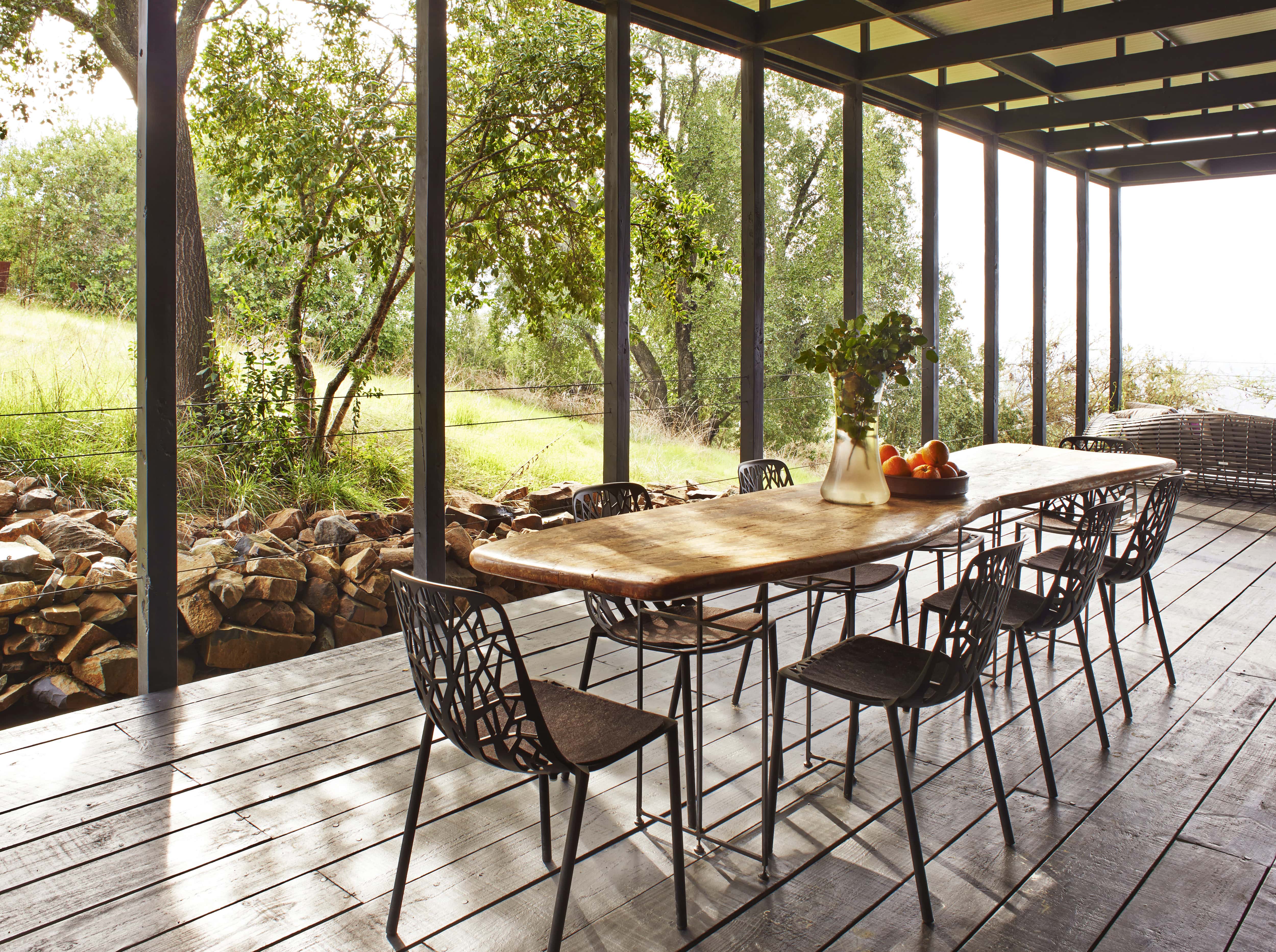 Large dining table under covered porch in backyard