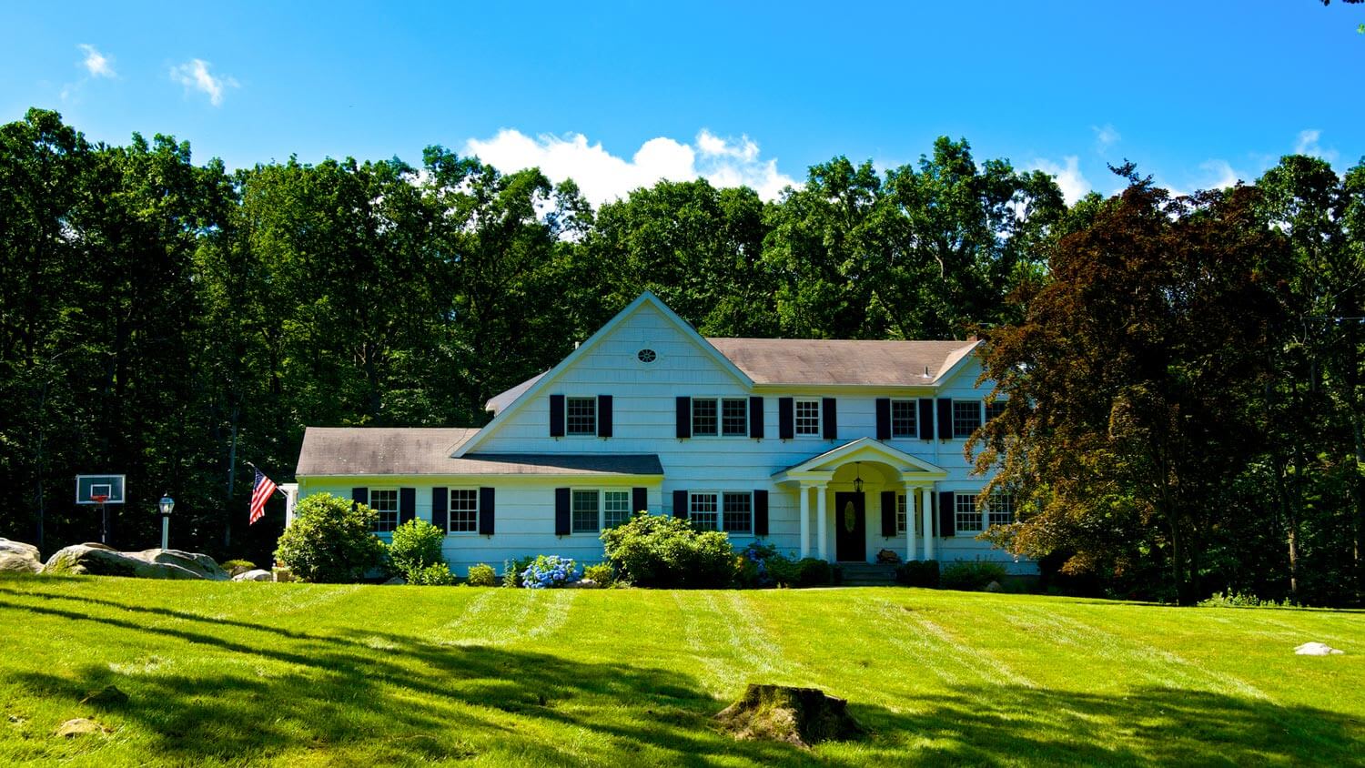 The exterior of a house with a tree stump in the front yard