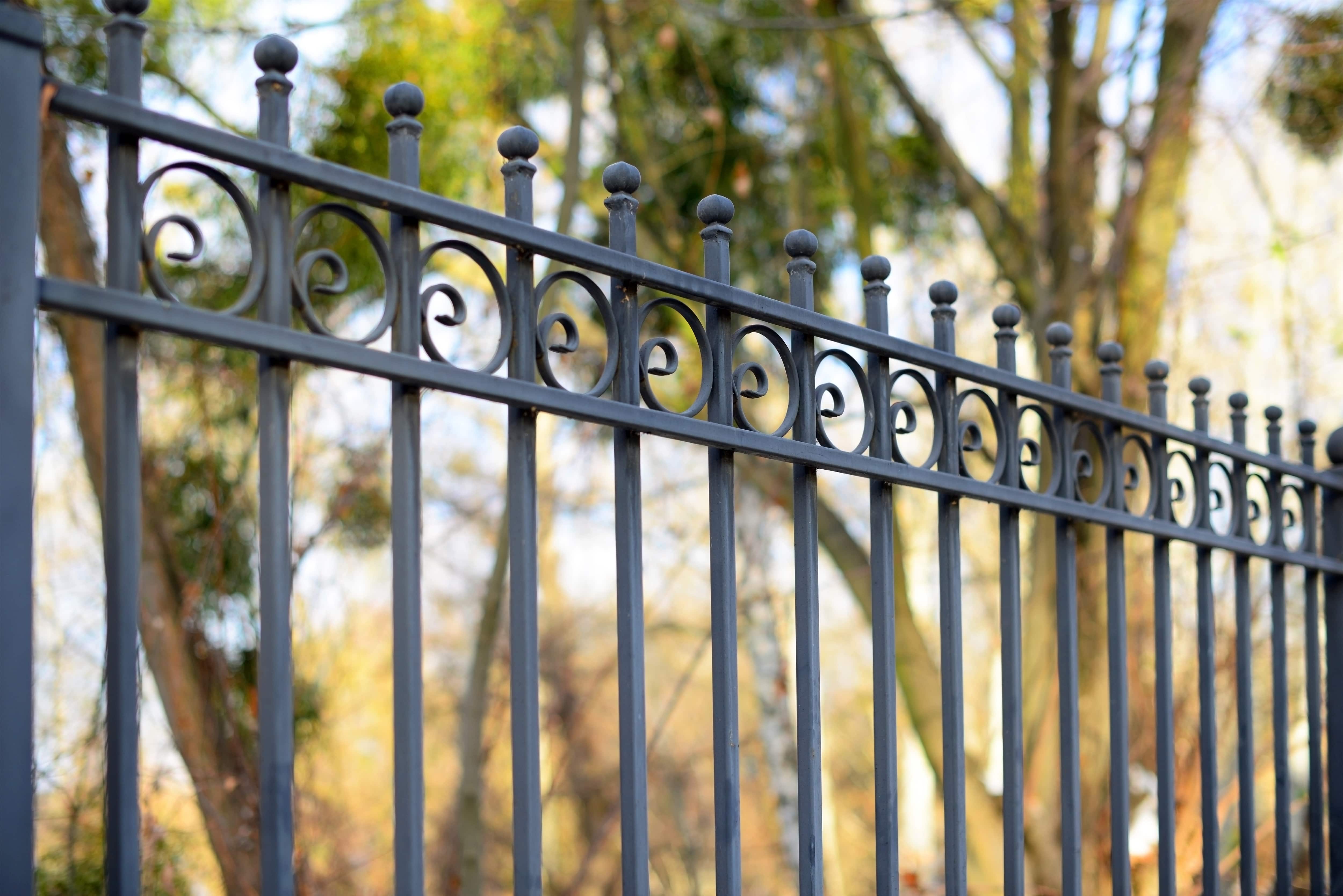 A close-up image of a steel fence with decorative bars