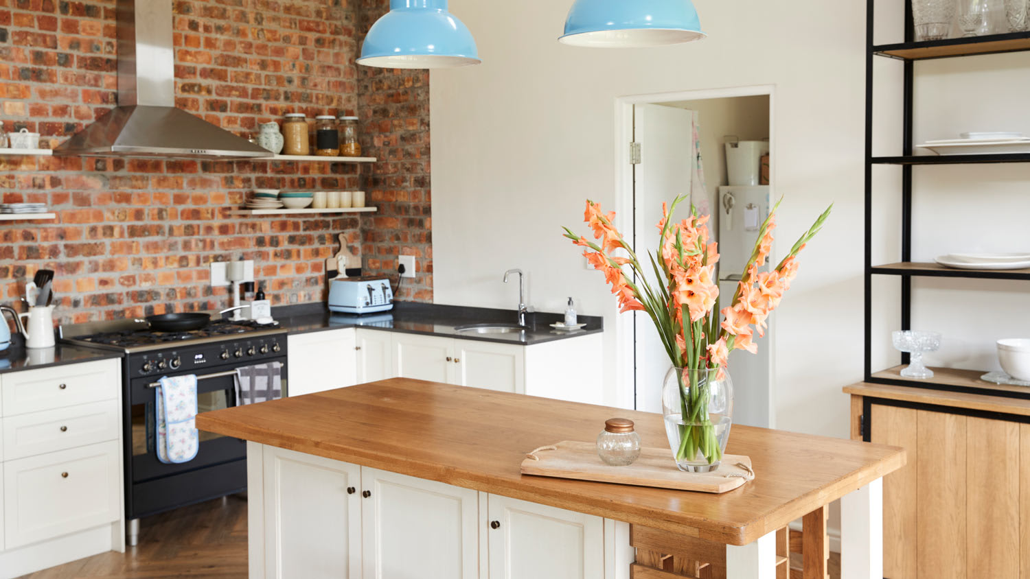 None The interior of an open kitchen plan with exposed brisk as backsplash