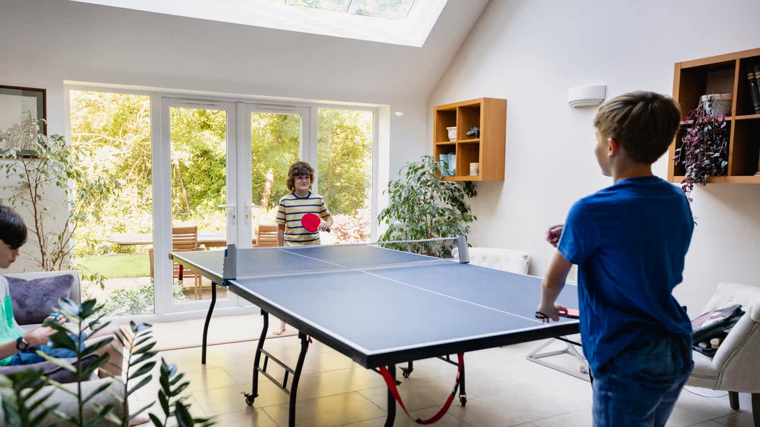 Two brothers playing ping pong in house’s game room