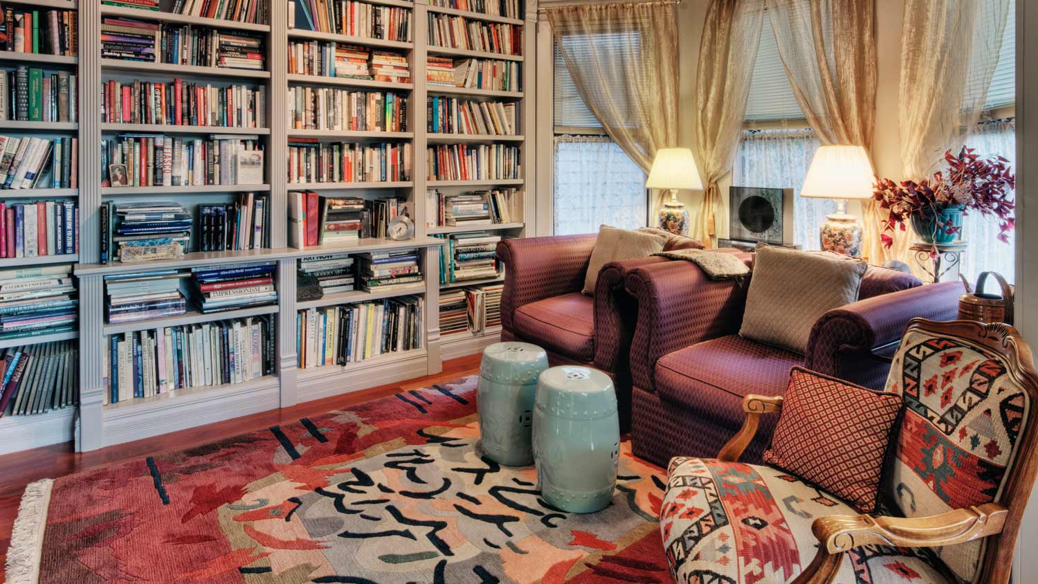 A library room with huge bookcase and two comfy armchairs