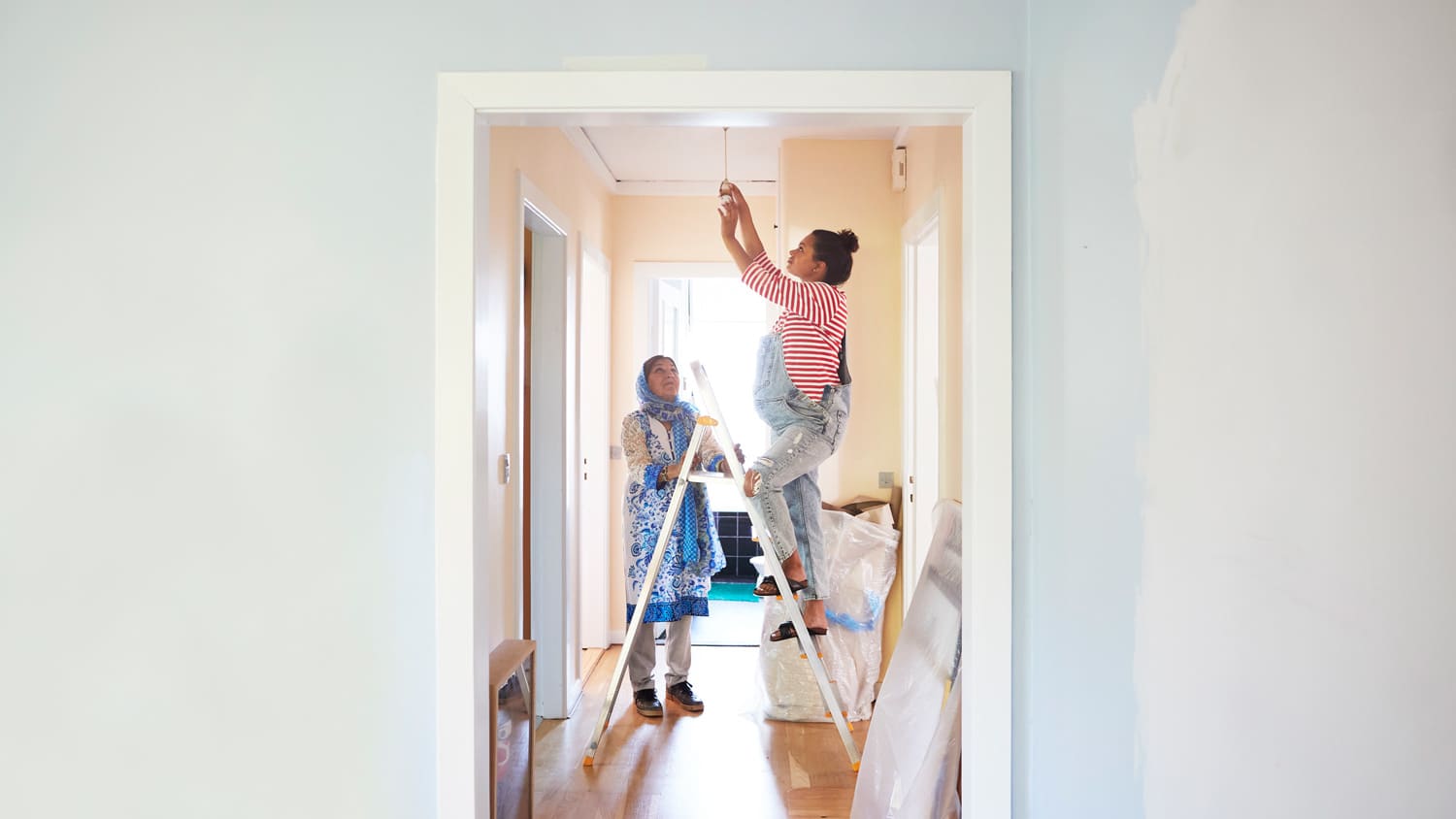 woman changing light bulb in kitchen