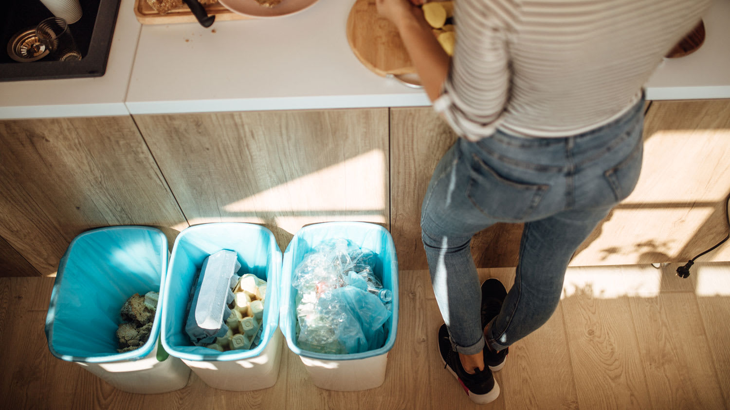 A woman cooking having garbage cans next to her