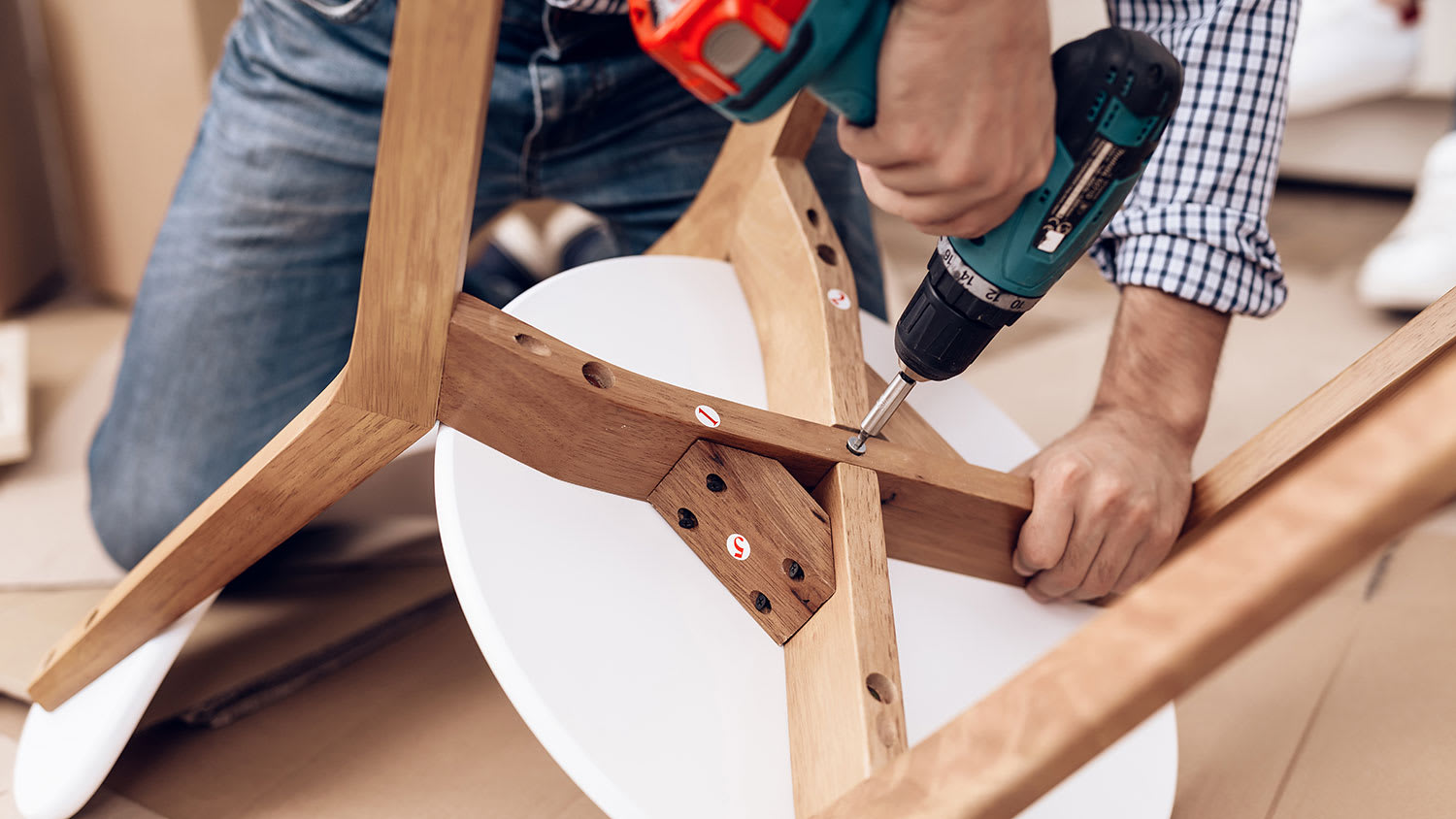 Handyman holding electric screwdriver assembling a chair