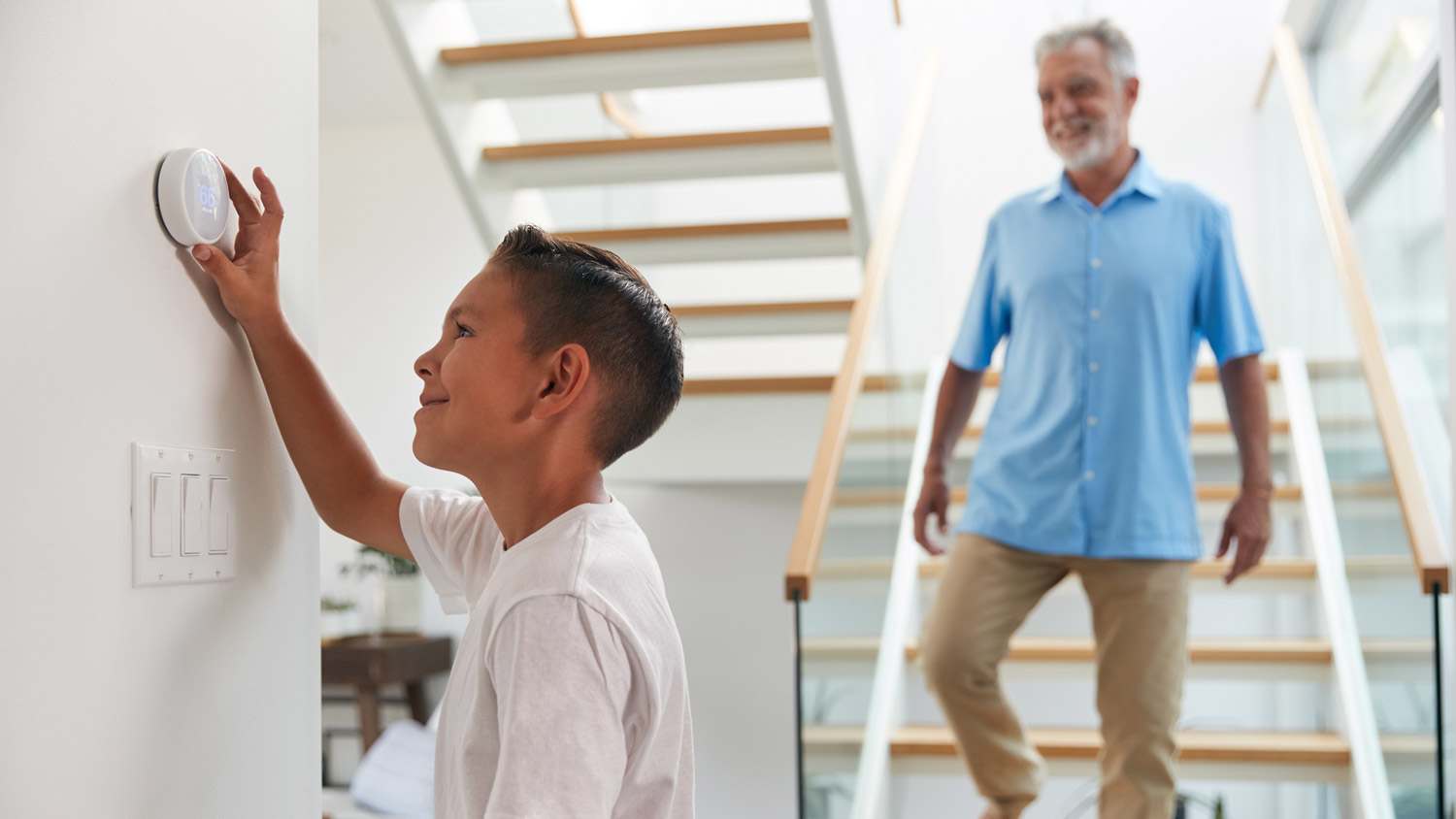 A kid adjusting the temperature of the house via a digital thermostat