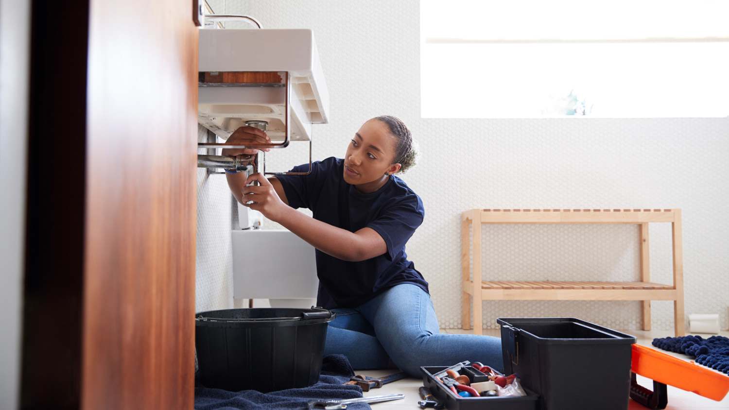A plumber unclogging a bathroom sink’s pipes
