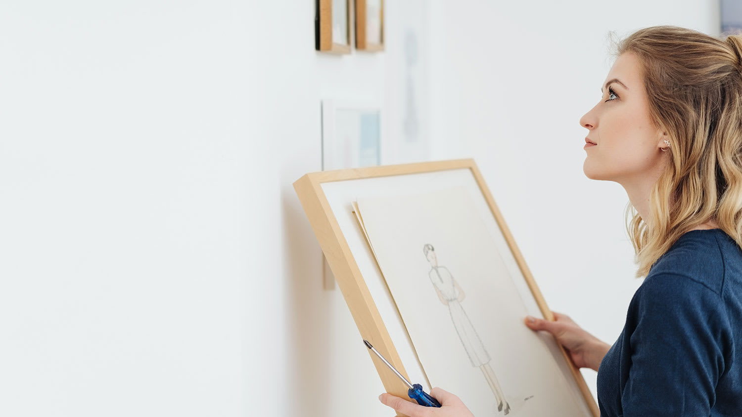 Woman mounting a picture frame on the wall