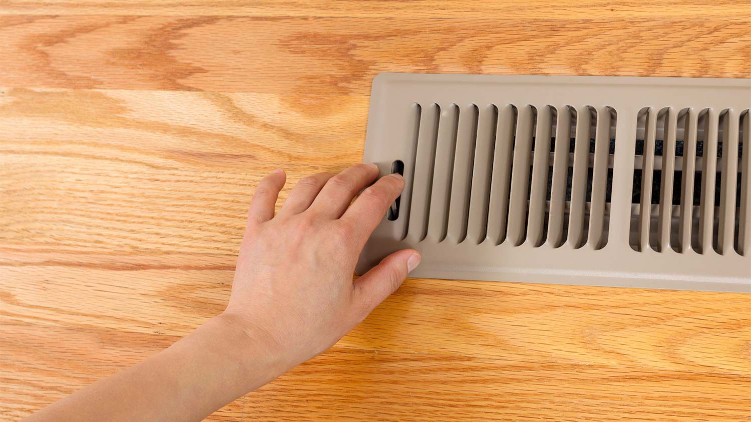 person opening up floor vent heater
