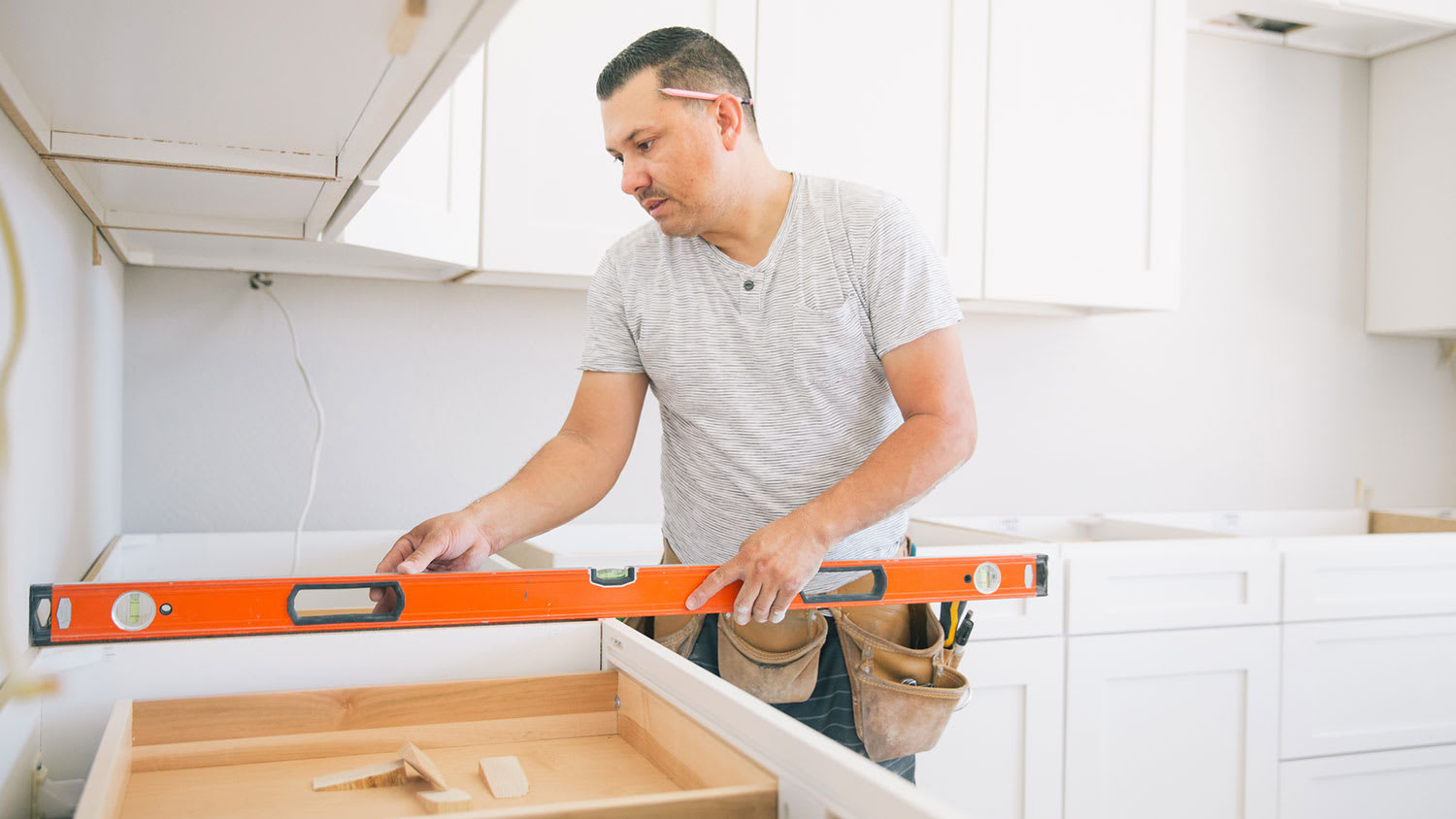 Worker using a level measuring tool to install kitchen
