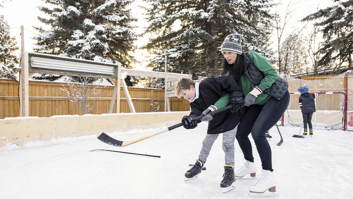mother and son playing ice hockey in yard