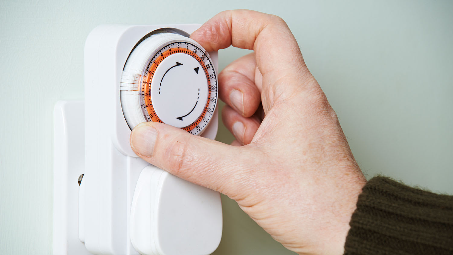 Man adjusting timer on electrical outlet