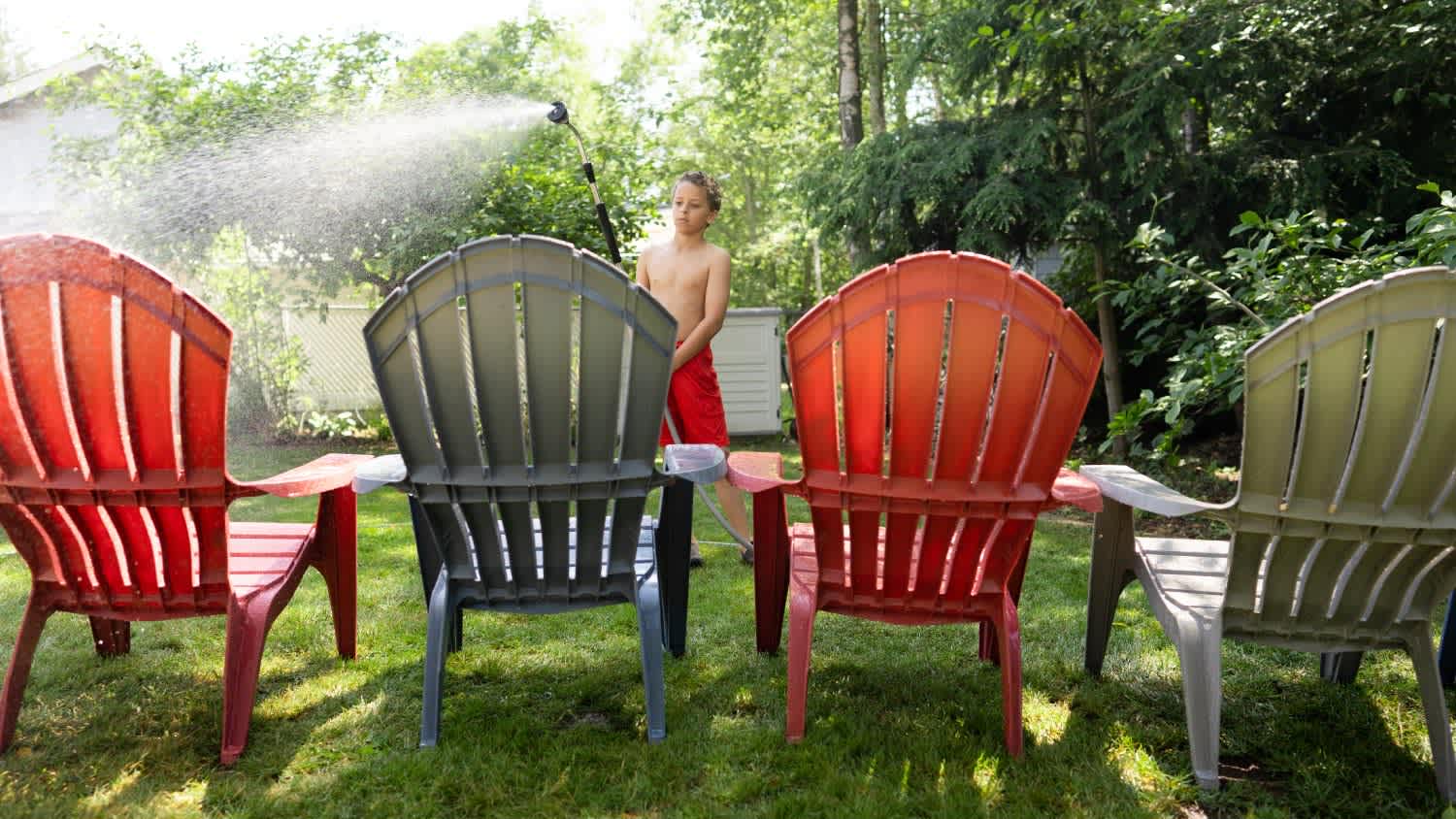 A boy washing plastic chairs