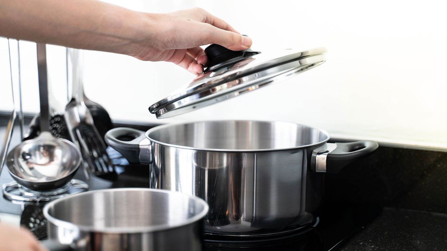 Hand holding saucepan lid