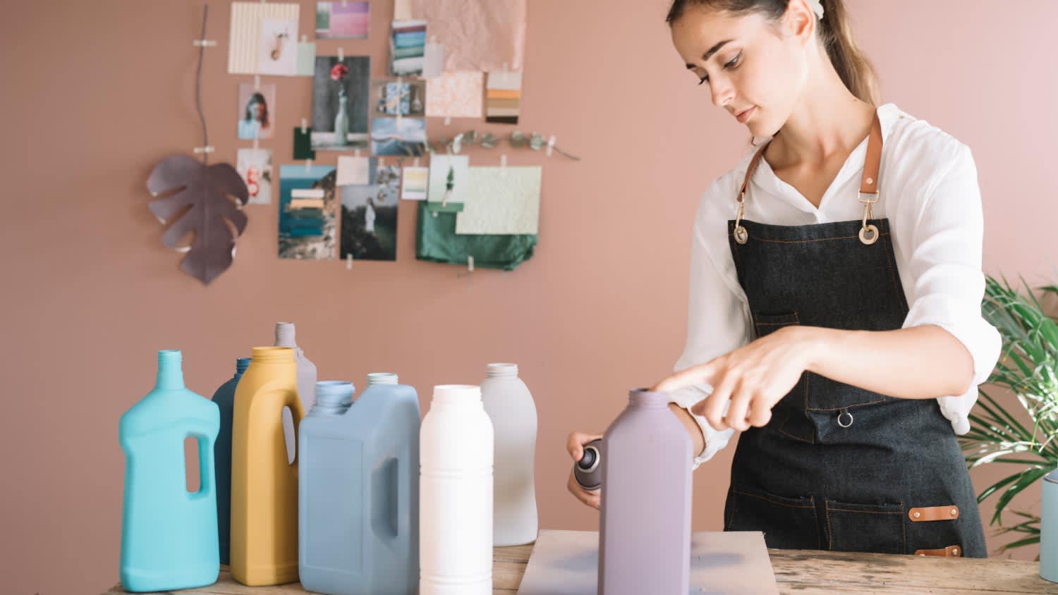 A woman painting a plastic bottle with spray