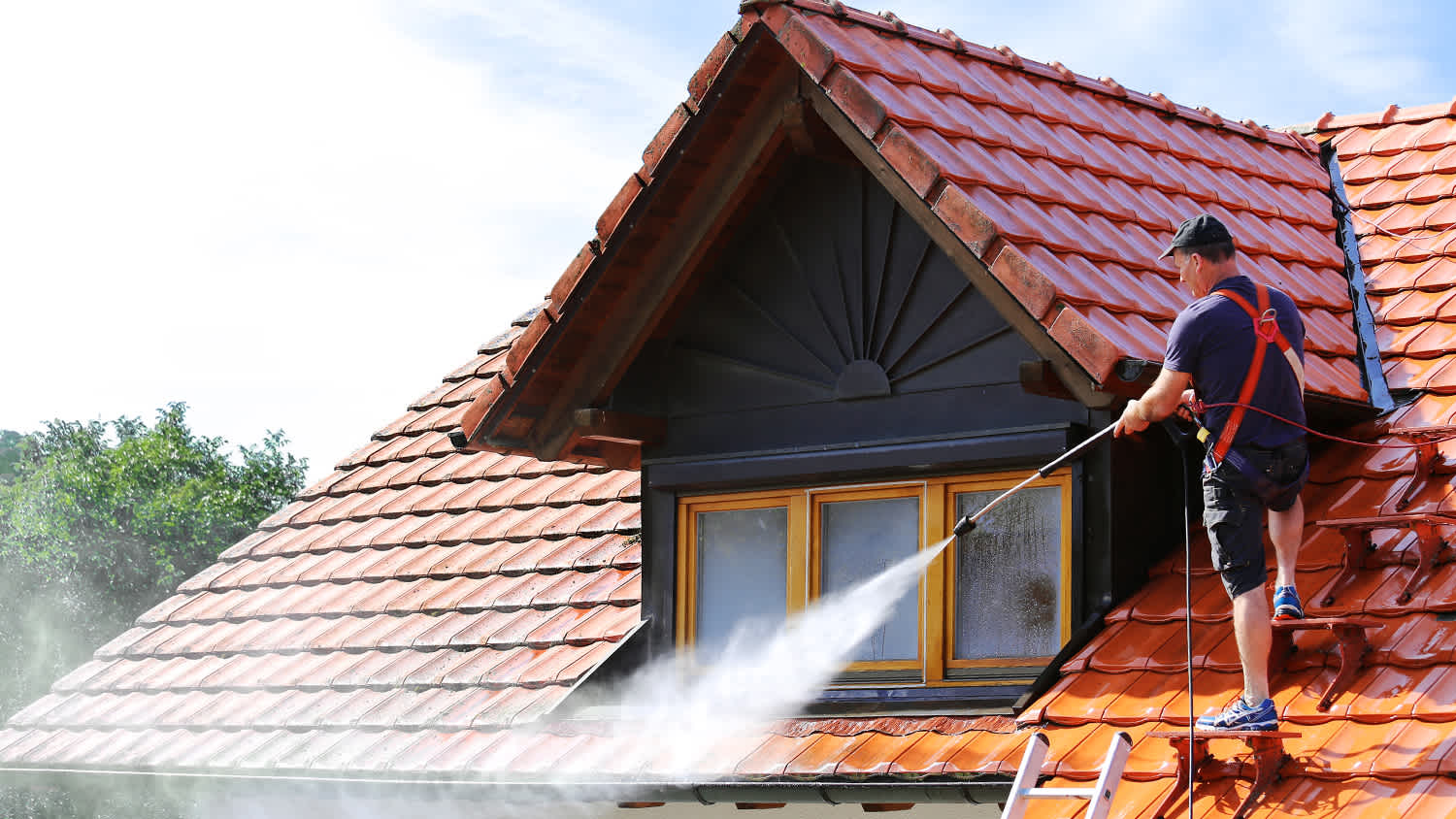 worker cleaning roof with high pressure hose