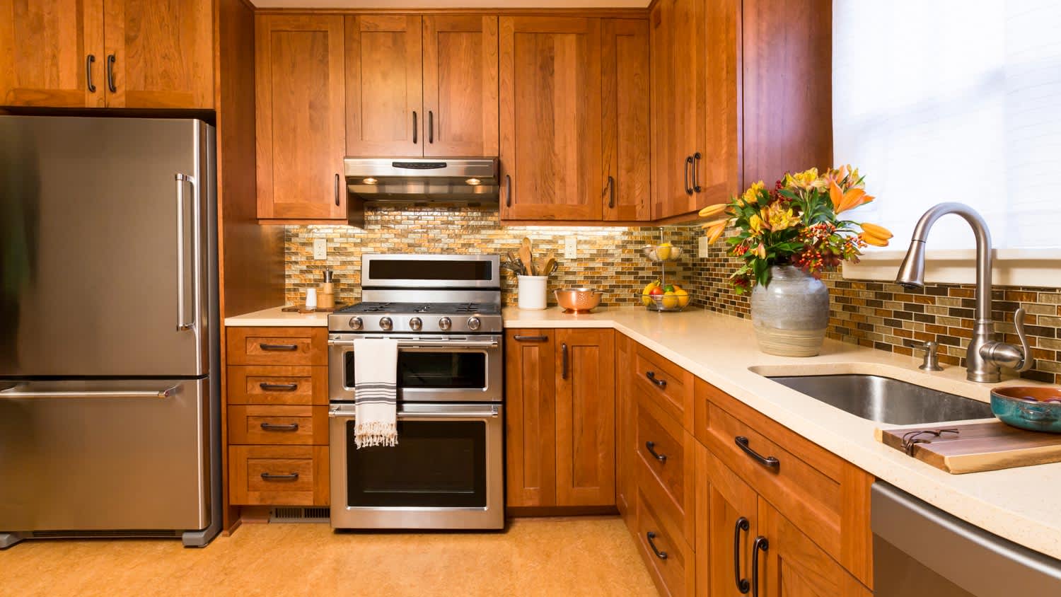 A kitchen with wooden cabinets and linoleum flooring