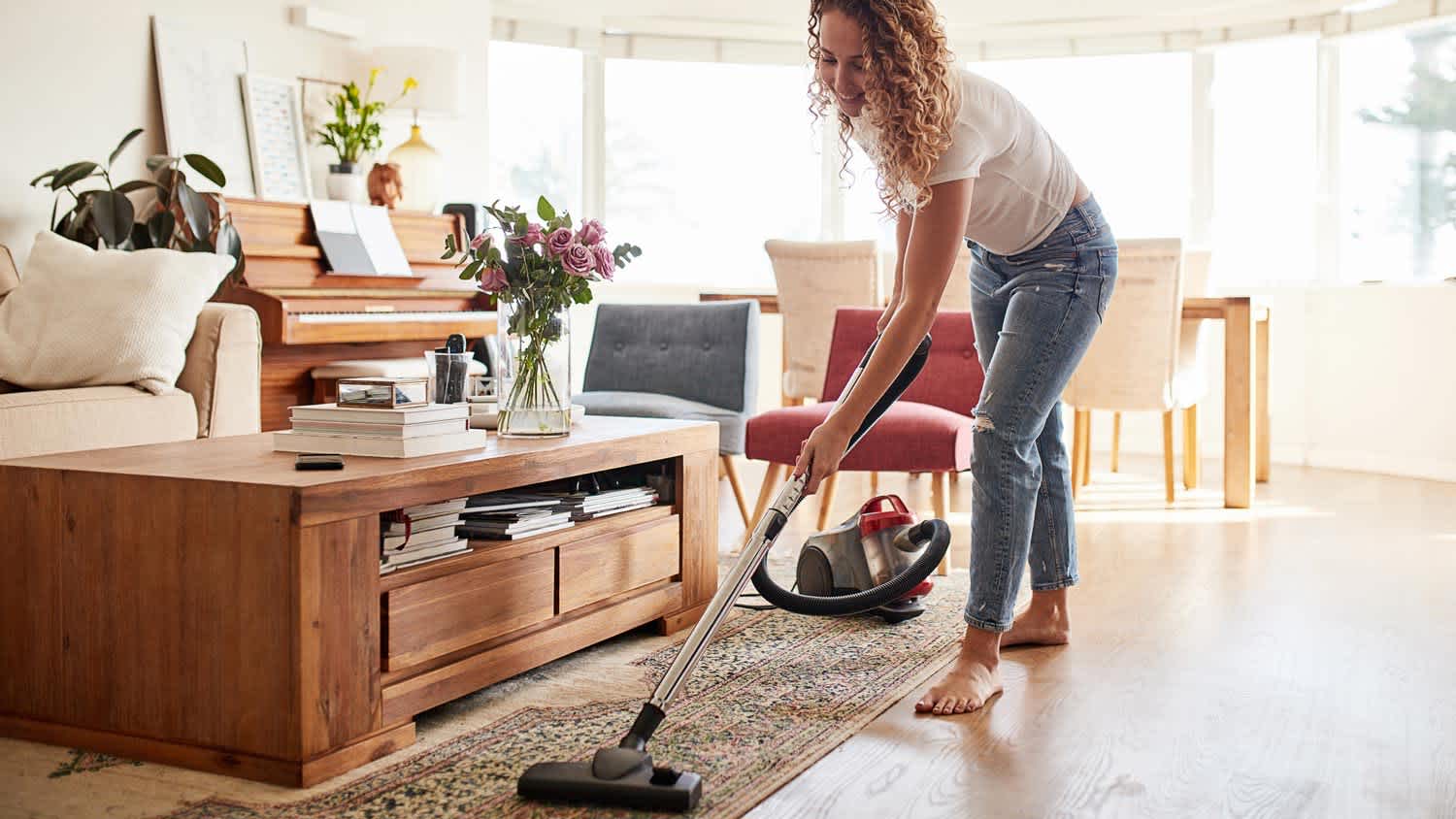 A woman vacuuming a carpet in the living room