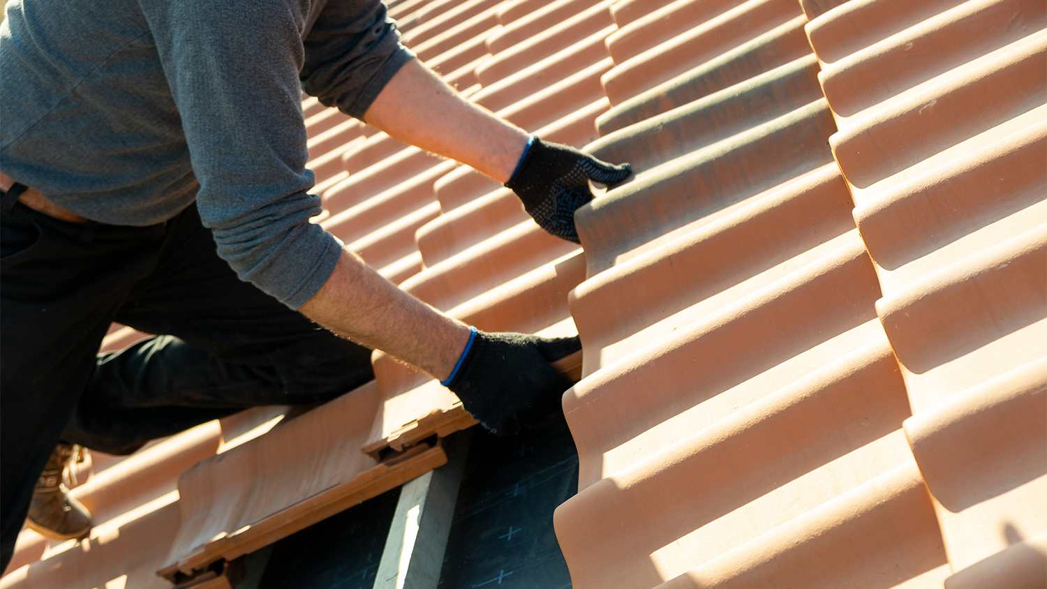 worker installing ceramic tiles on roof