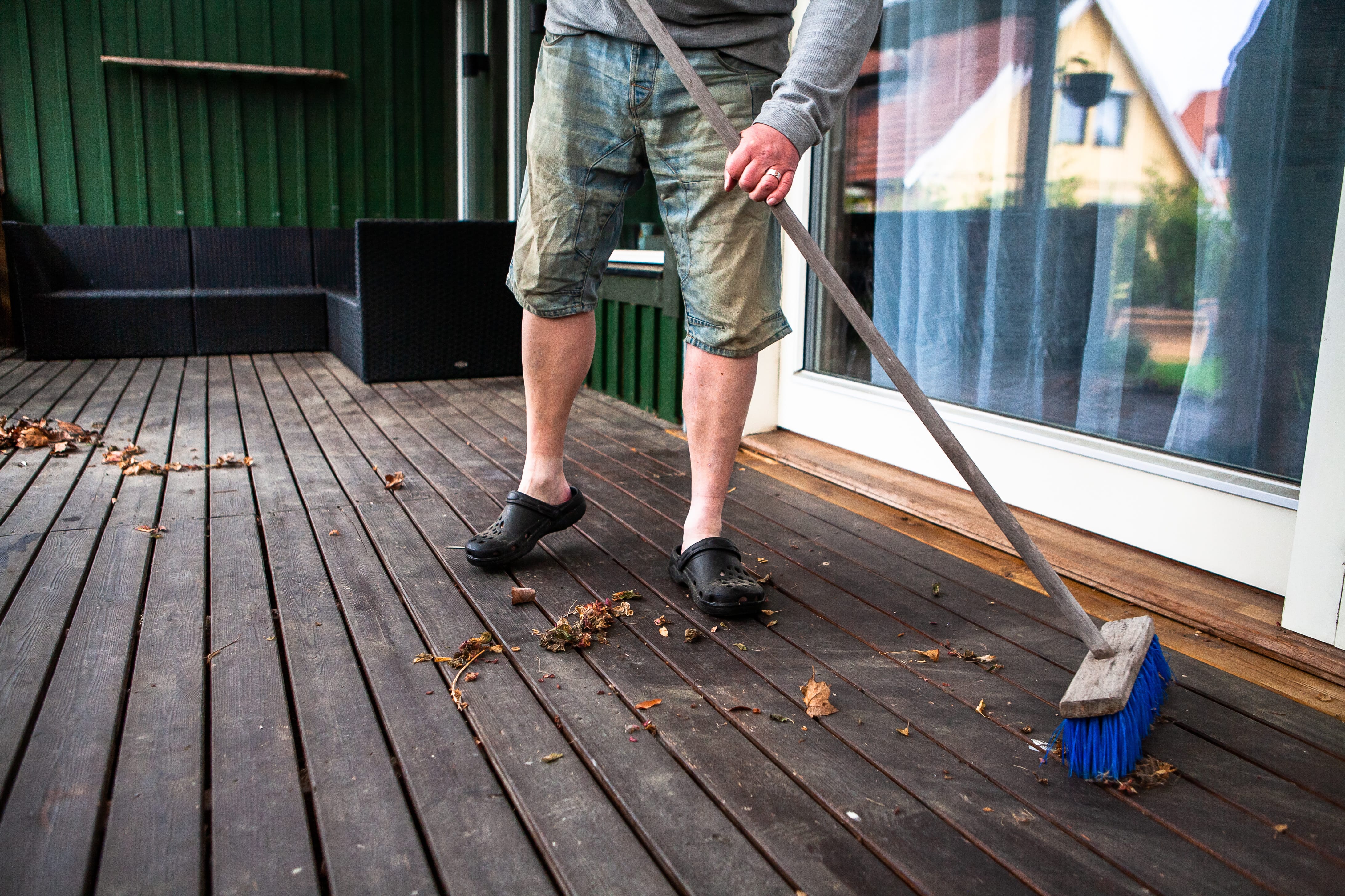 Man sweeping debris off of his deck with a broom