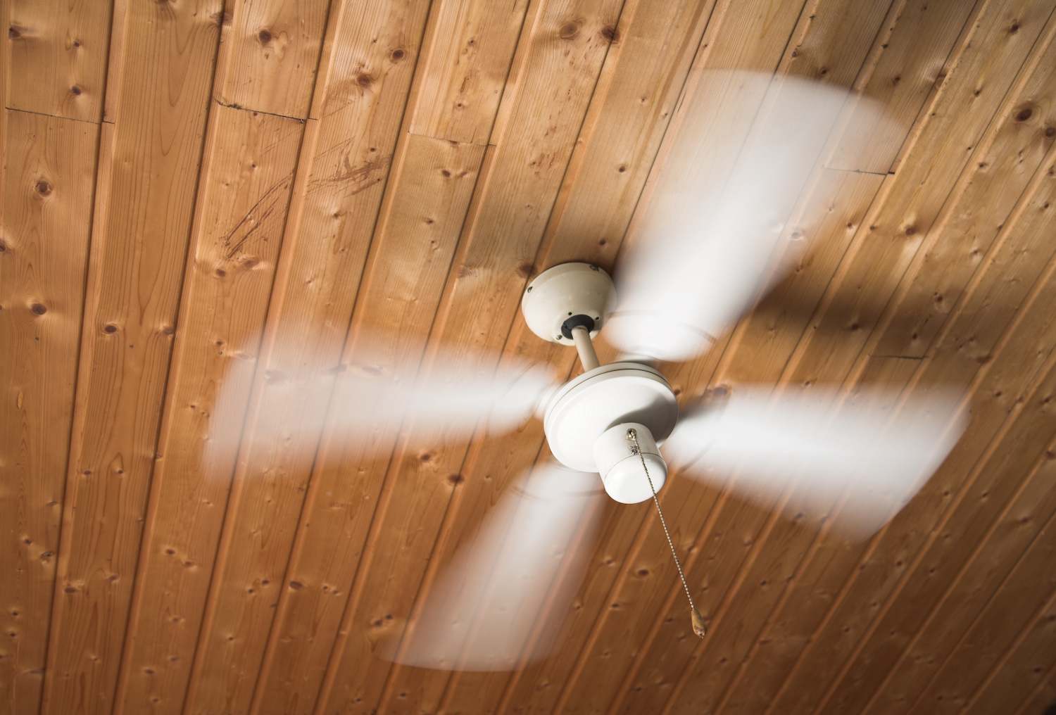 Ceiling fan in motion mounted on wooden ceiling