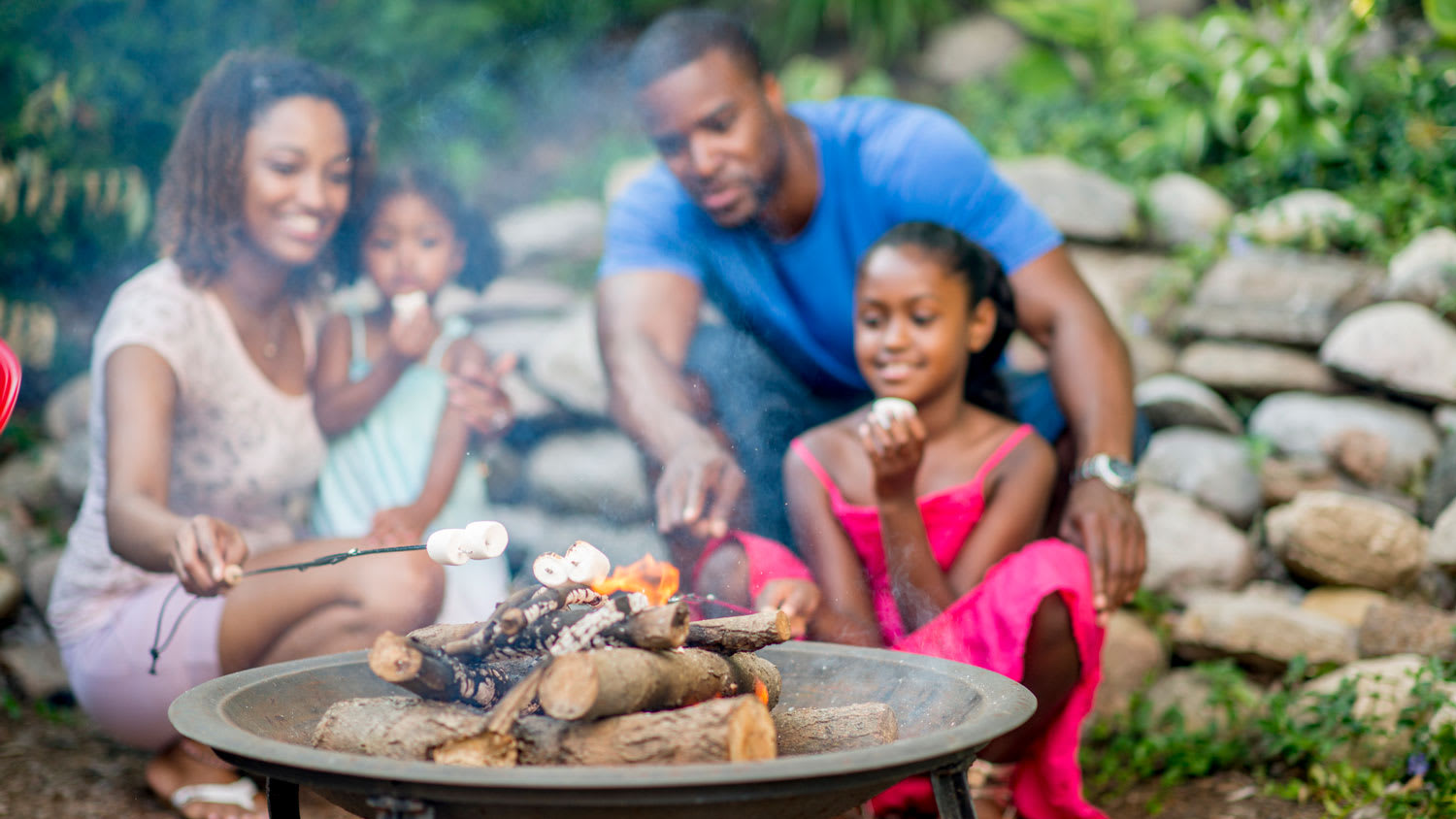 A family roasting marshmallows in a fire pit in their backyard