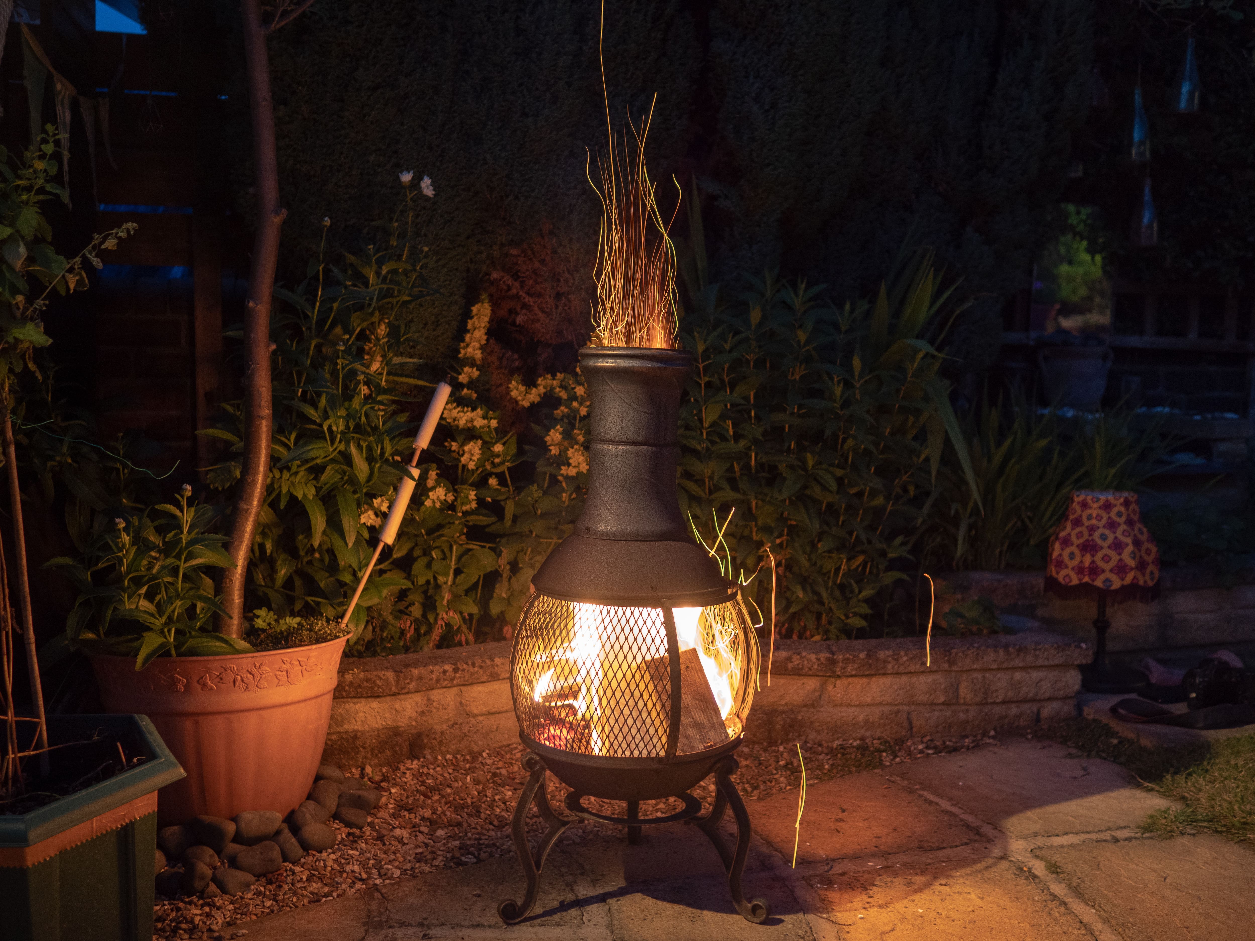 A black metal chiminea fire pit on a stone slab