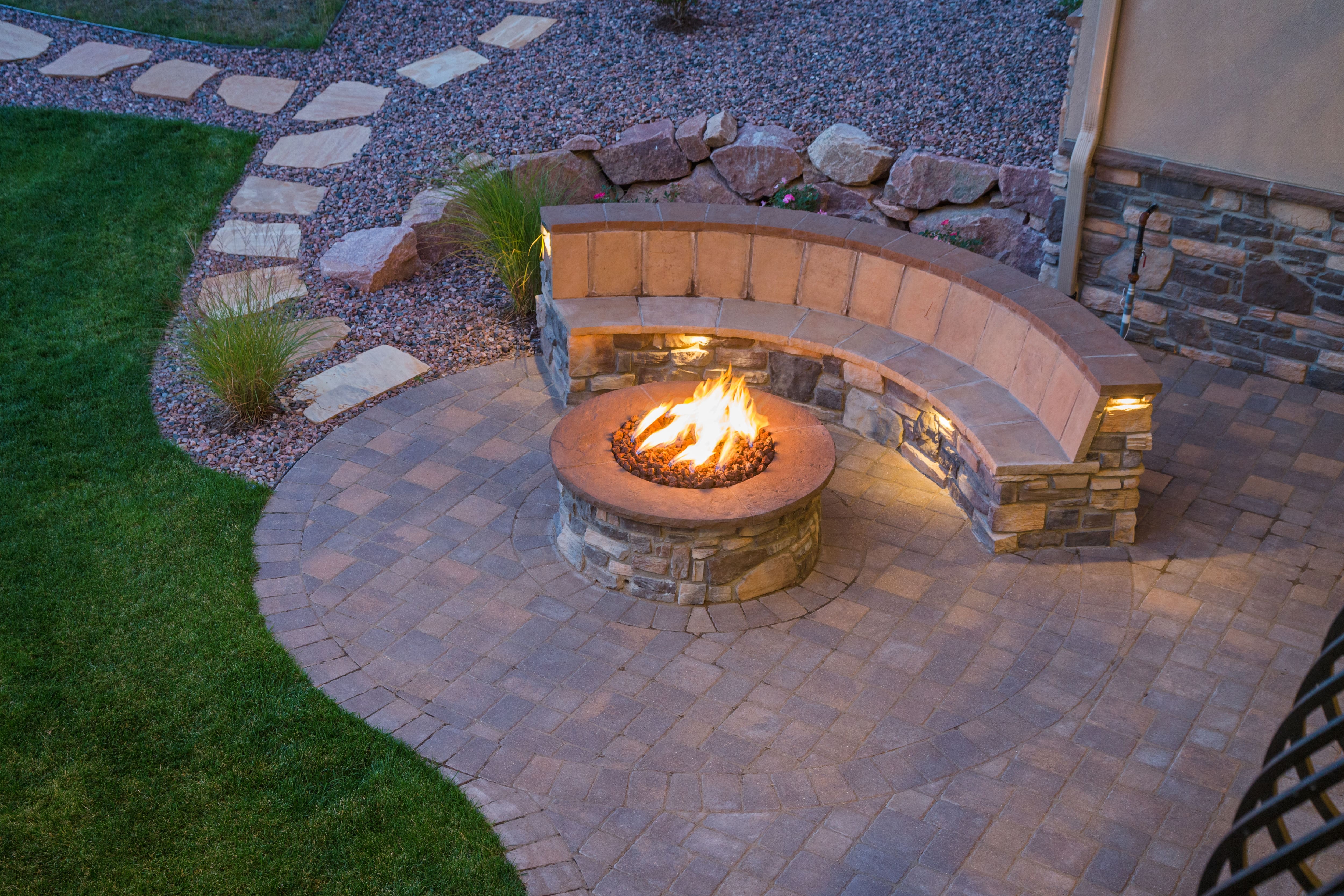 An outdoor platform, fire pit, and built-in seating made entirely of stone