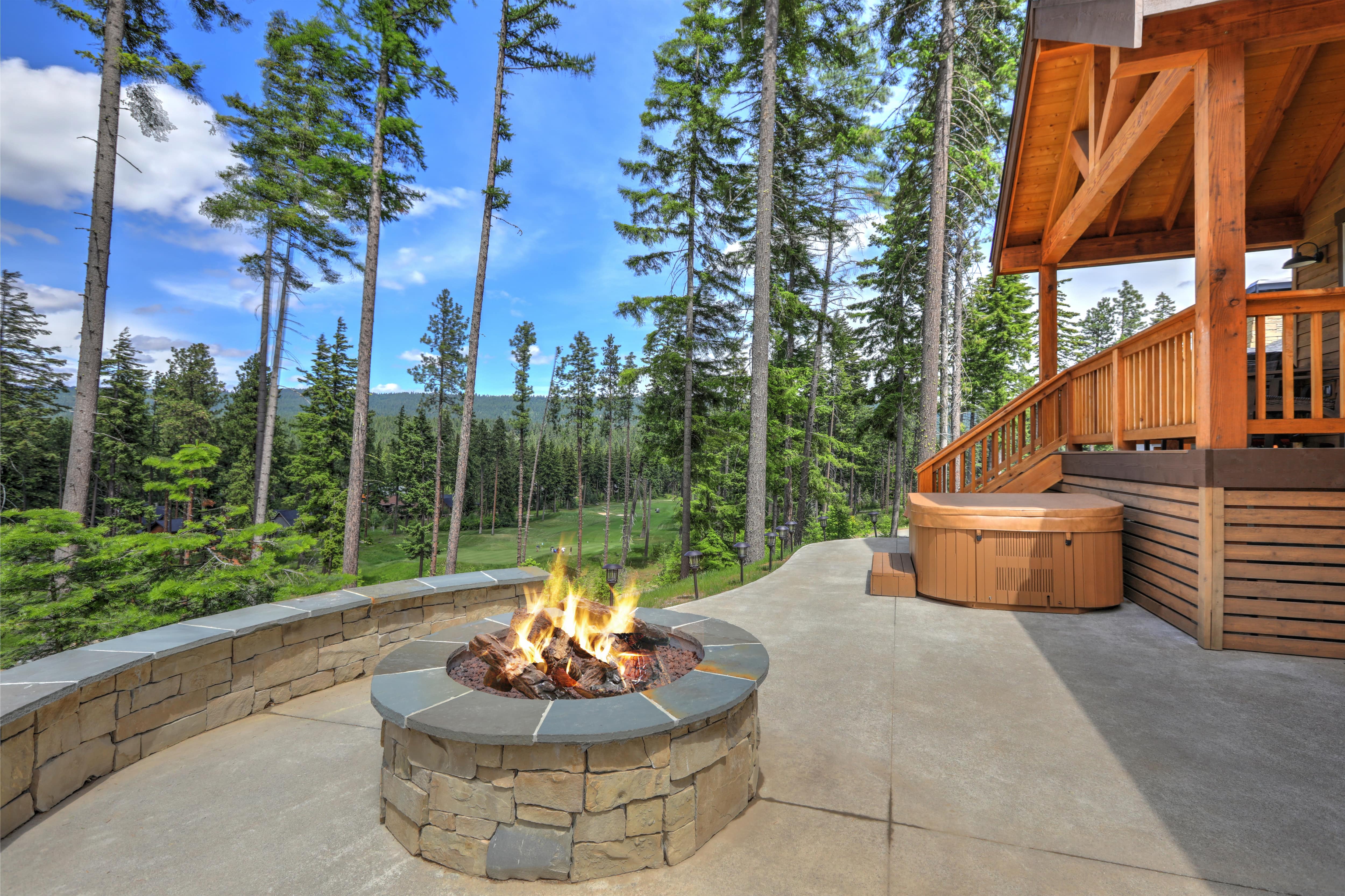 A mountain cabin with a covered hot tub and a stone fire pit