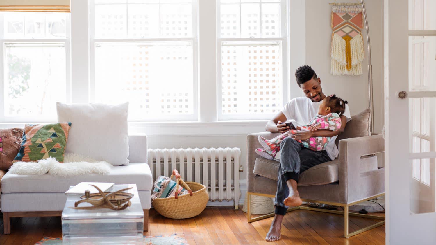Father looking at daughter while holding tablet computer in living room