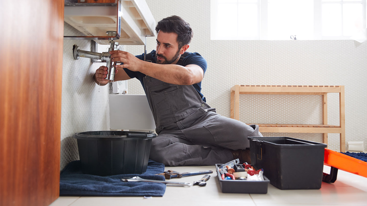 Plumber is fixing a leaking sink in the bathroom