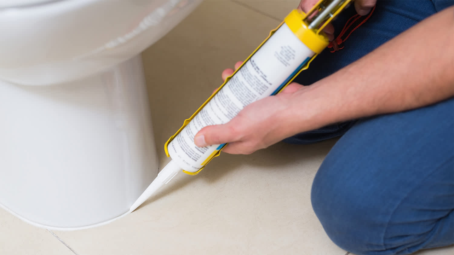 man fixing toilet with silicone
