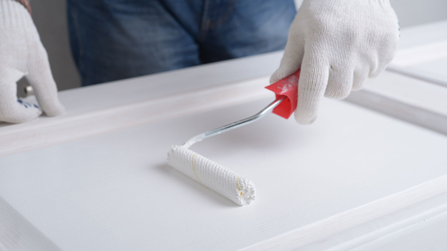 Closeup of a hand painting door with roller