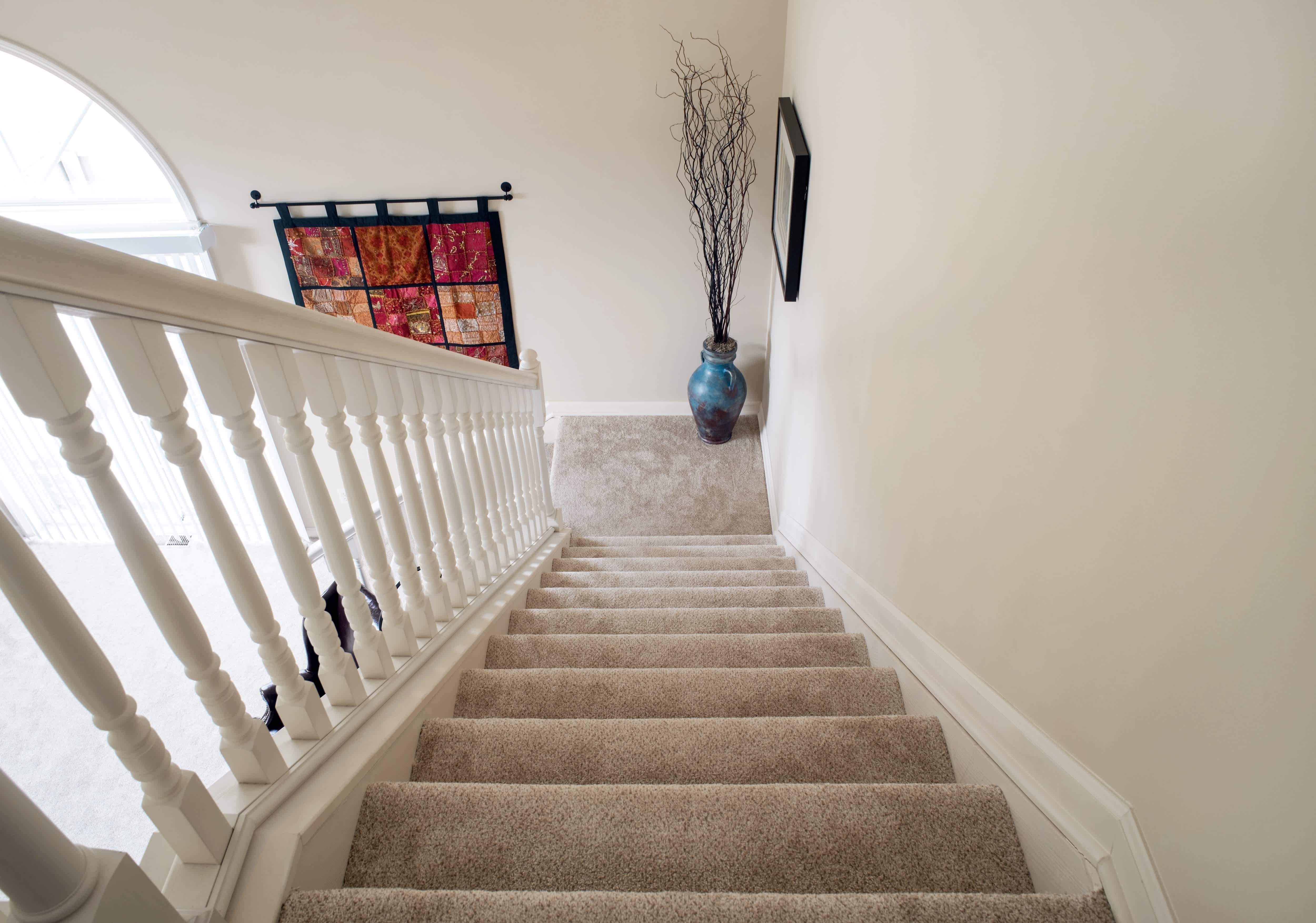 An interior staircase with decorative sticks in a blue vase on the corner step