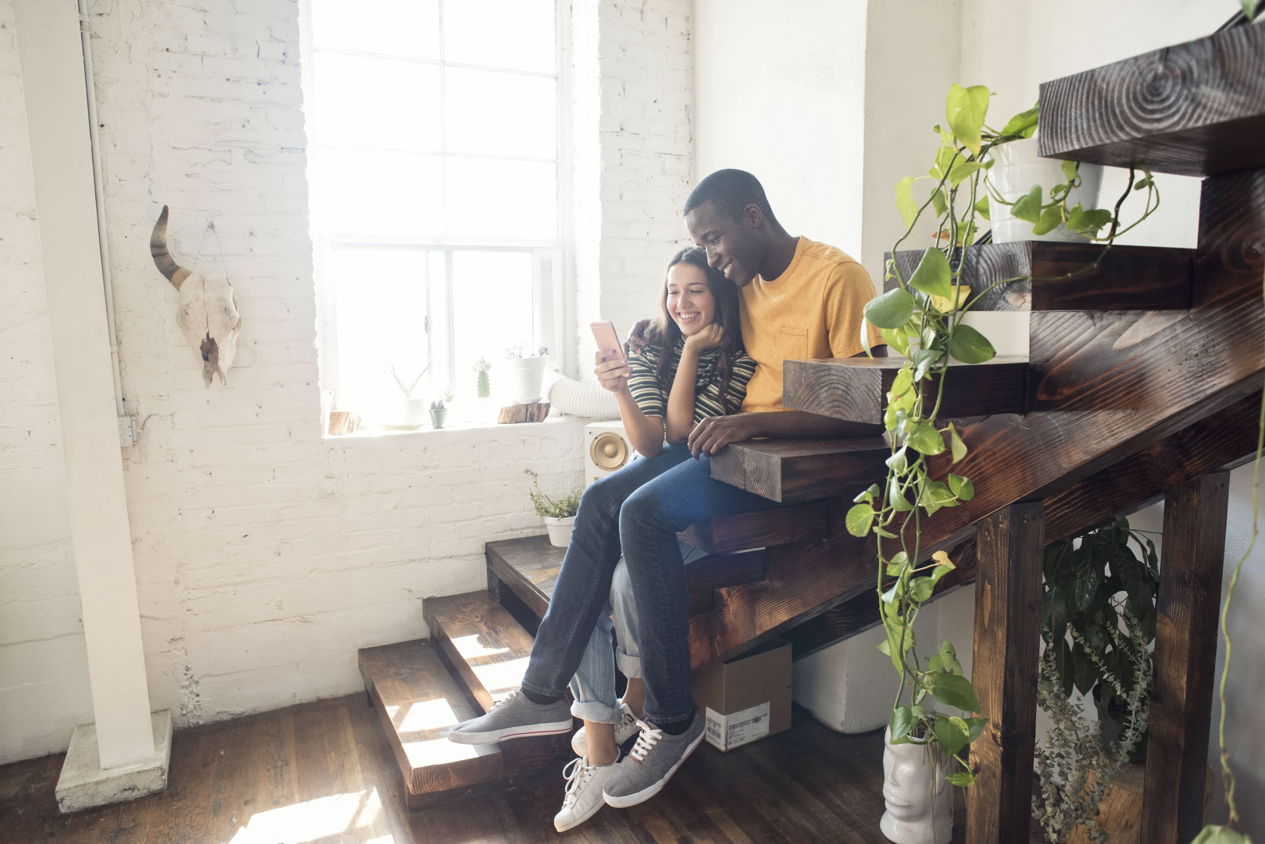 A couple sitting on a loft staircase decorated with potted plants