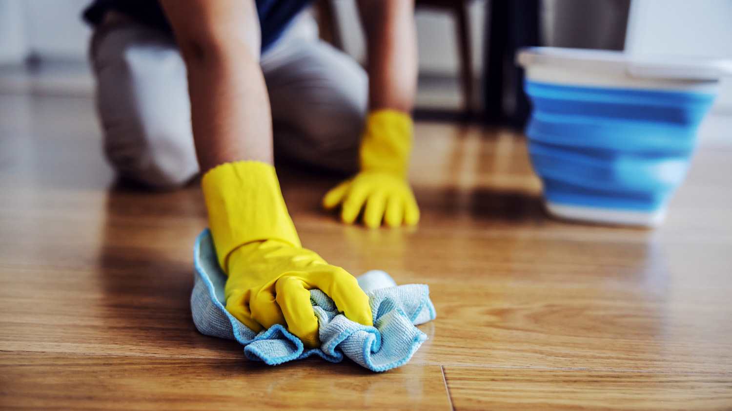 A man on his knees waxing with a microfibre a wood floor