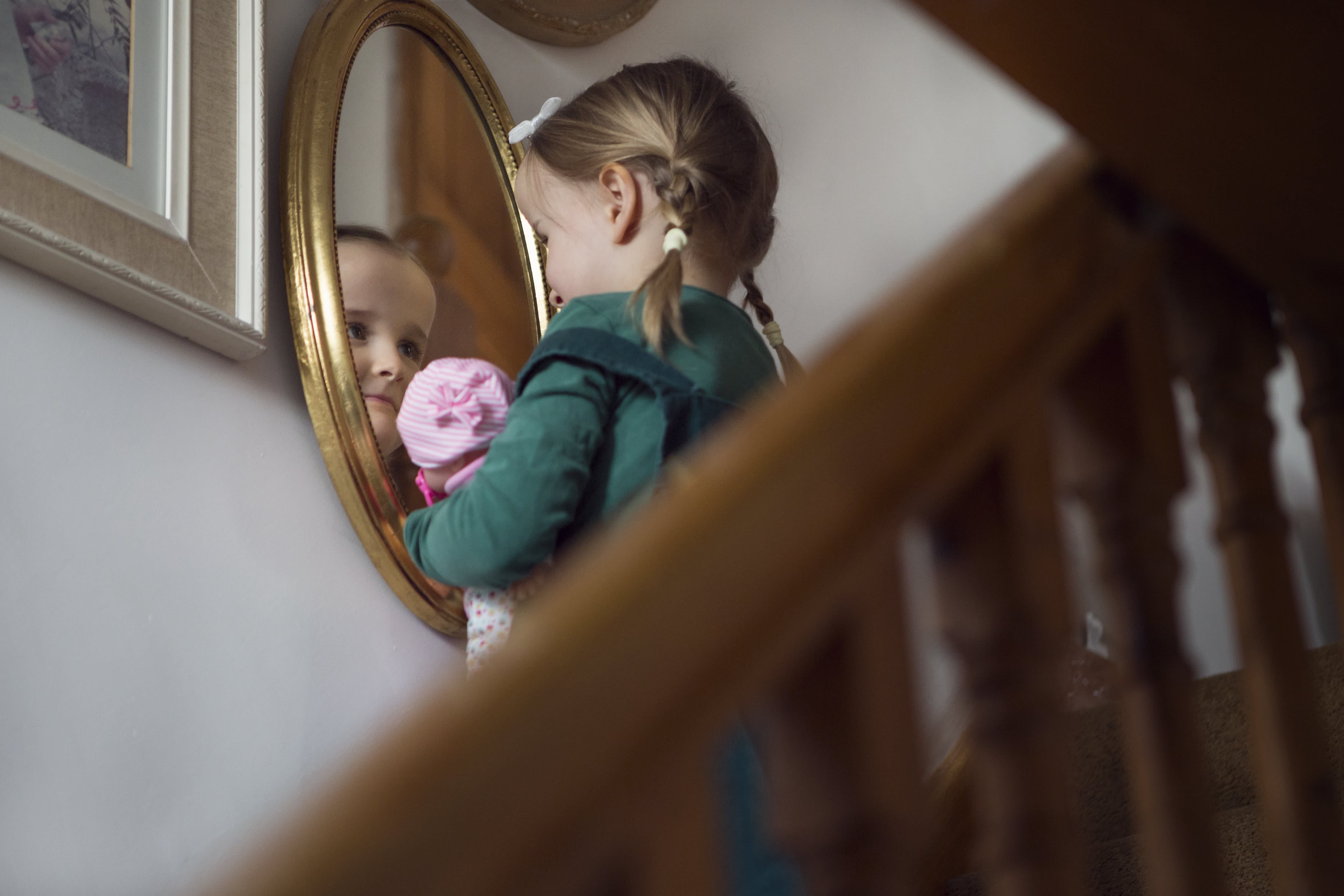 A little girl looking into a gallery wall mirror