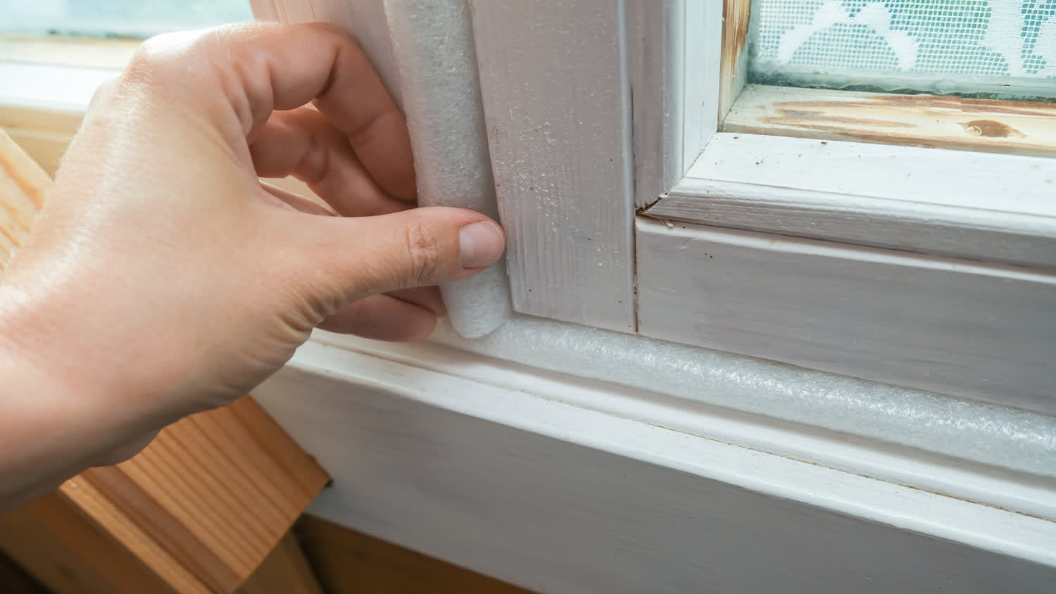 A woman inspecting the weatherstripping on a window
