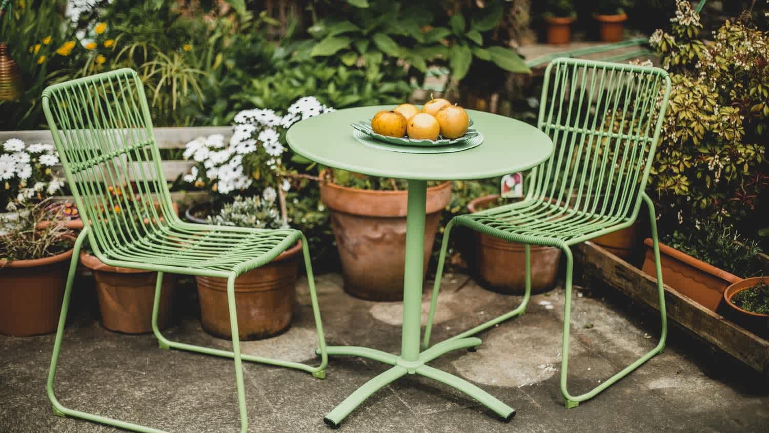 Two green design chairs and a table for a patio
