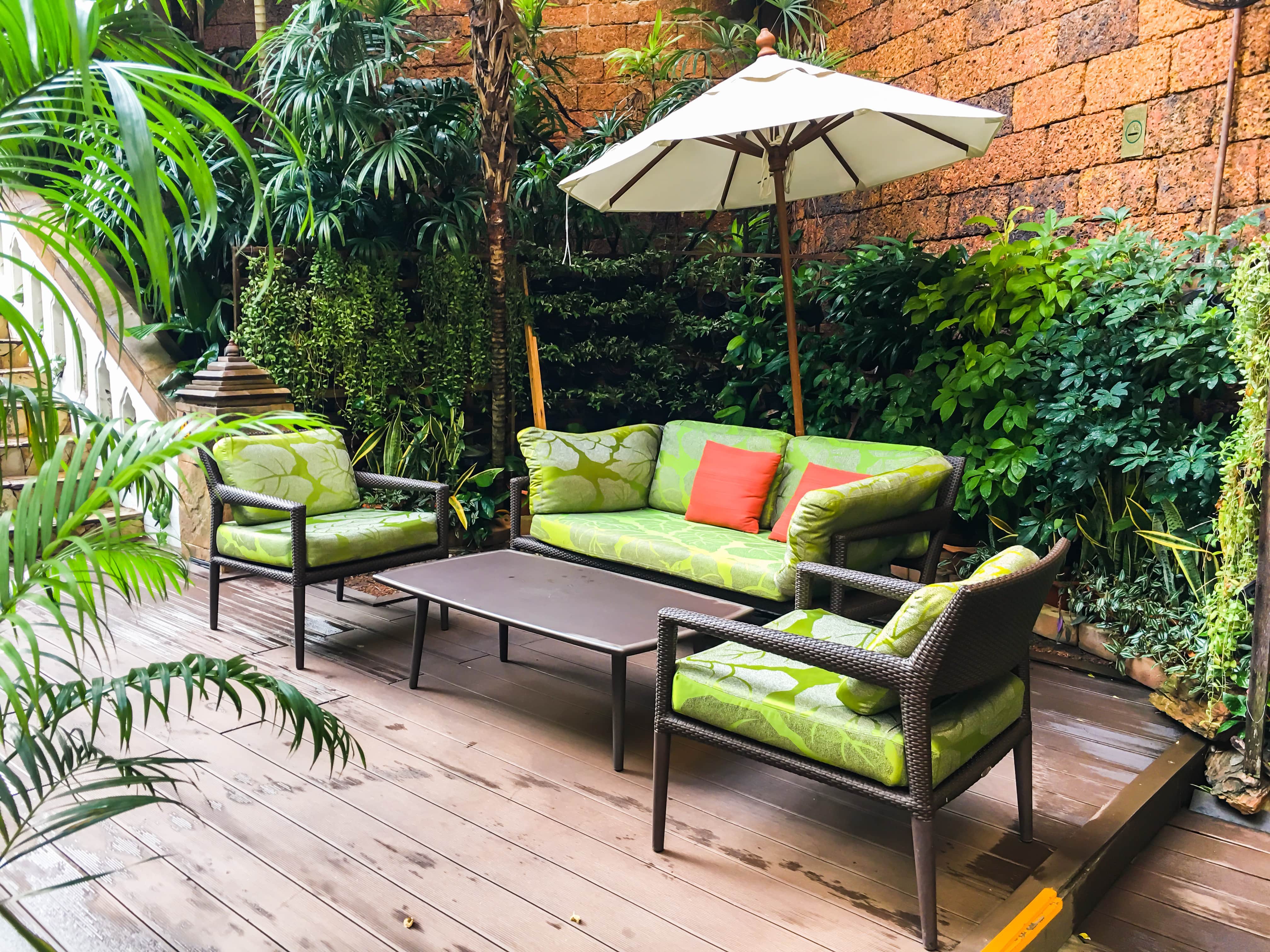 Outdoor furniture with a table, couch and seat with green cushions and red pillows